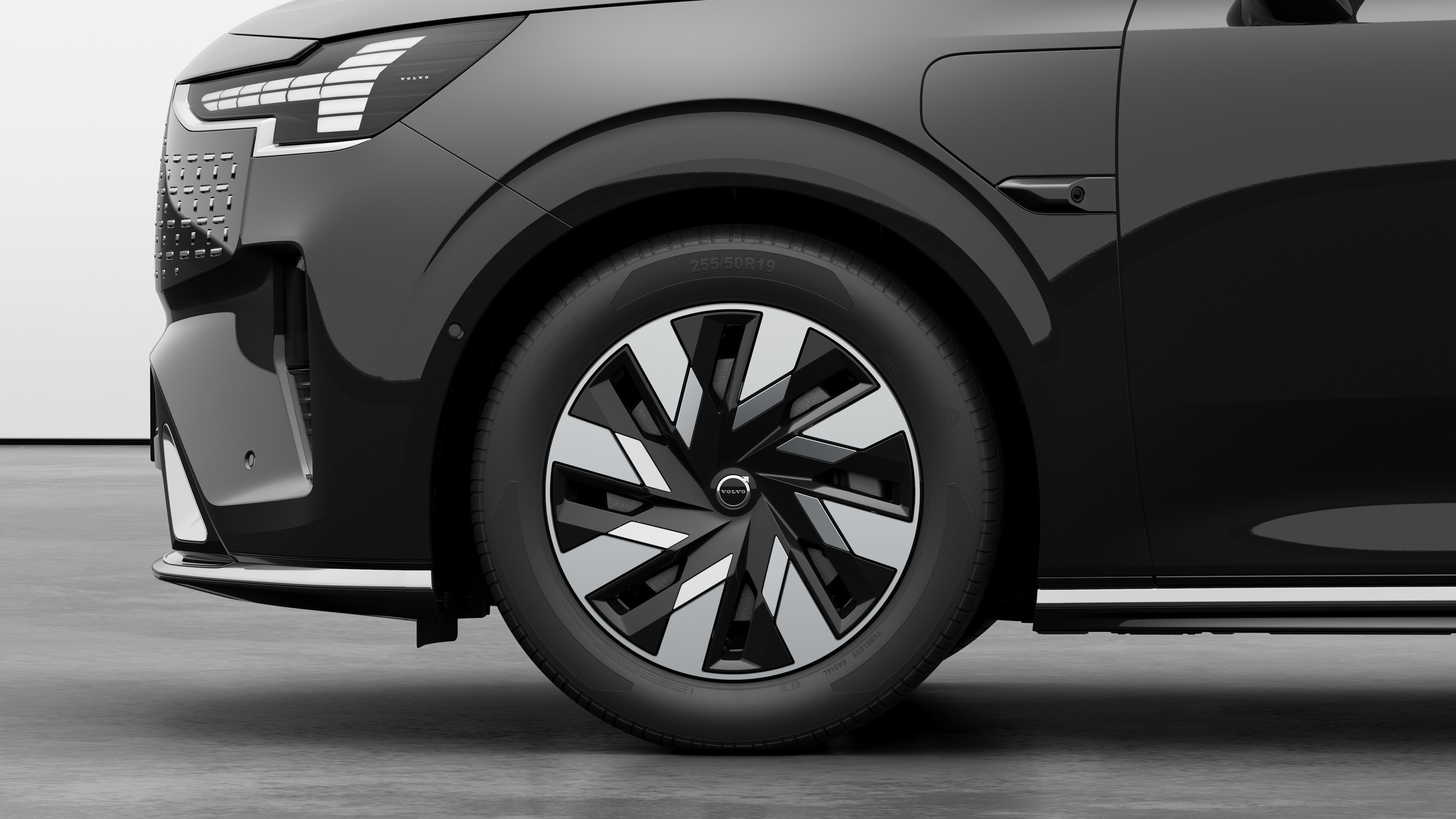 沃尔沃汽车外部侧视图聚焦于前轮和挡泥板，背景为朴素的工作室背景。
