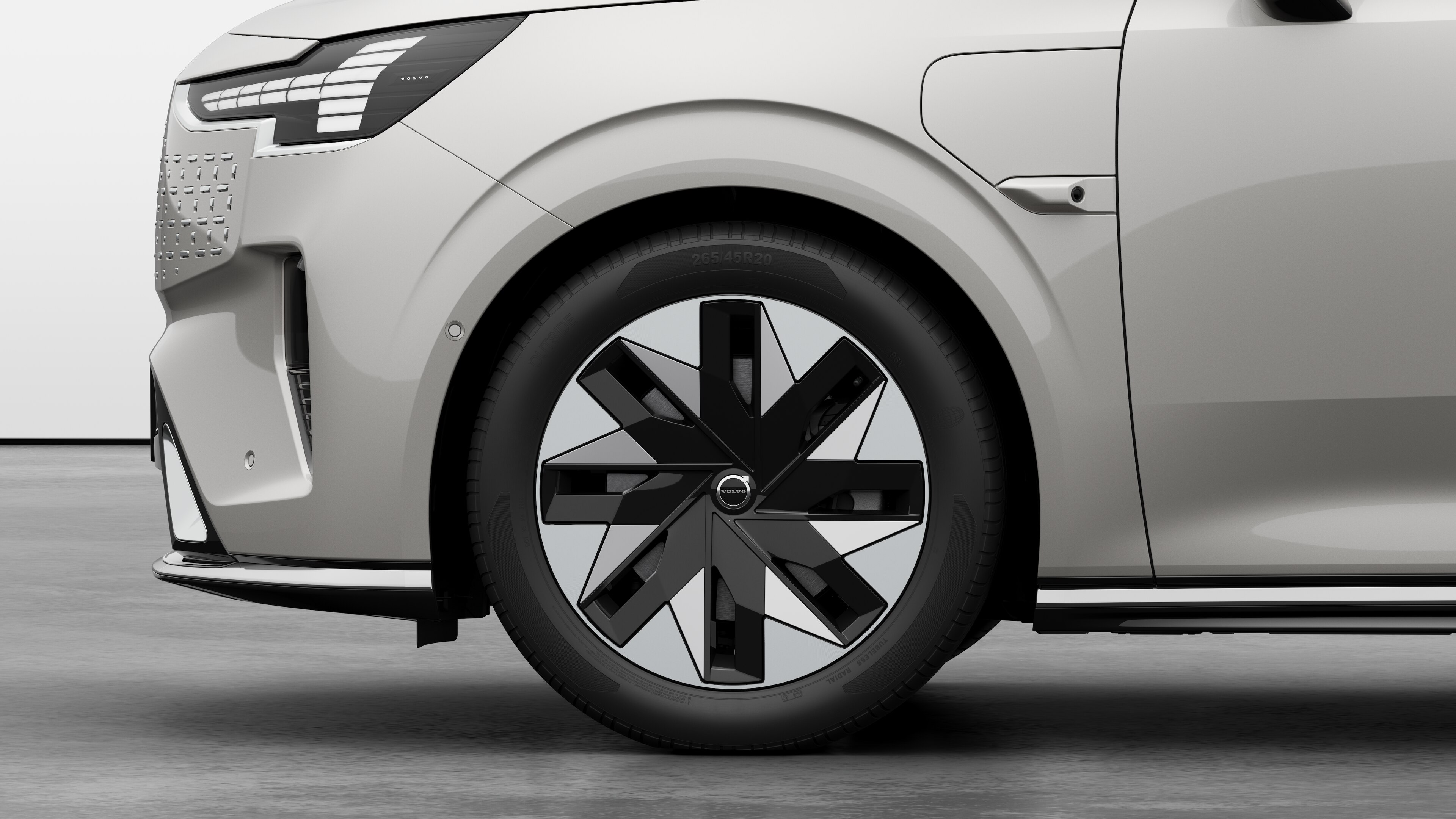 沃尔沃汽车外部侧视图聚焦于前轮和挡泥板，背景为朴素的工作室背景。