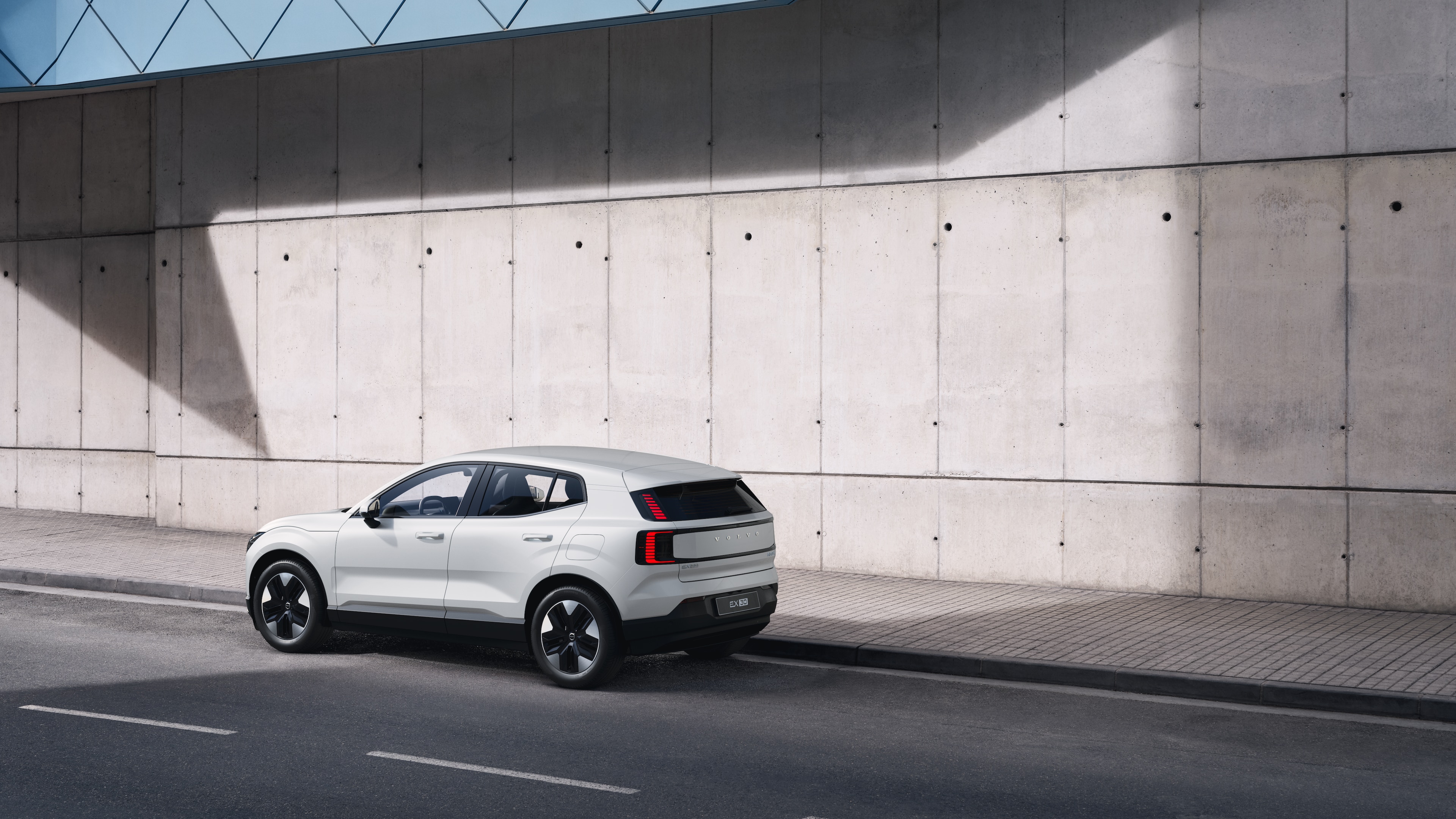 沃尔沃汽车在后方四分之三视图中停在城市街道背景的混凝土墙上。