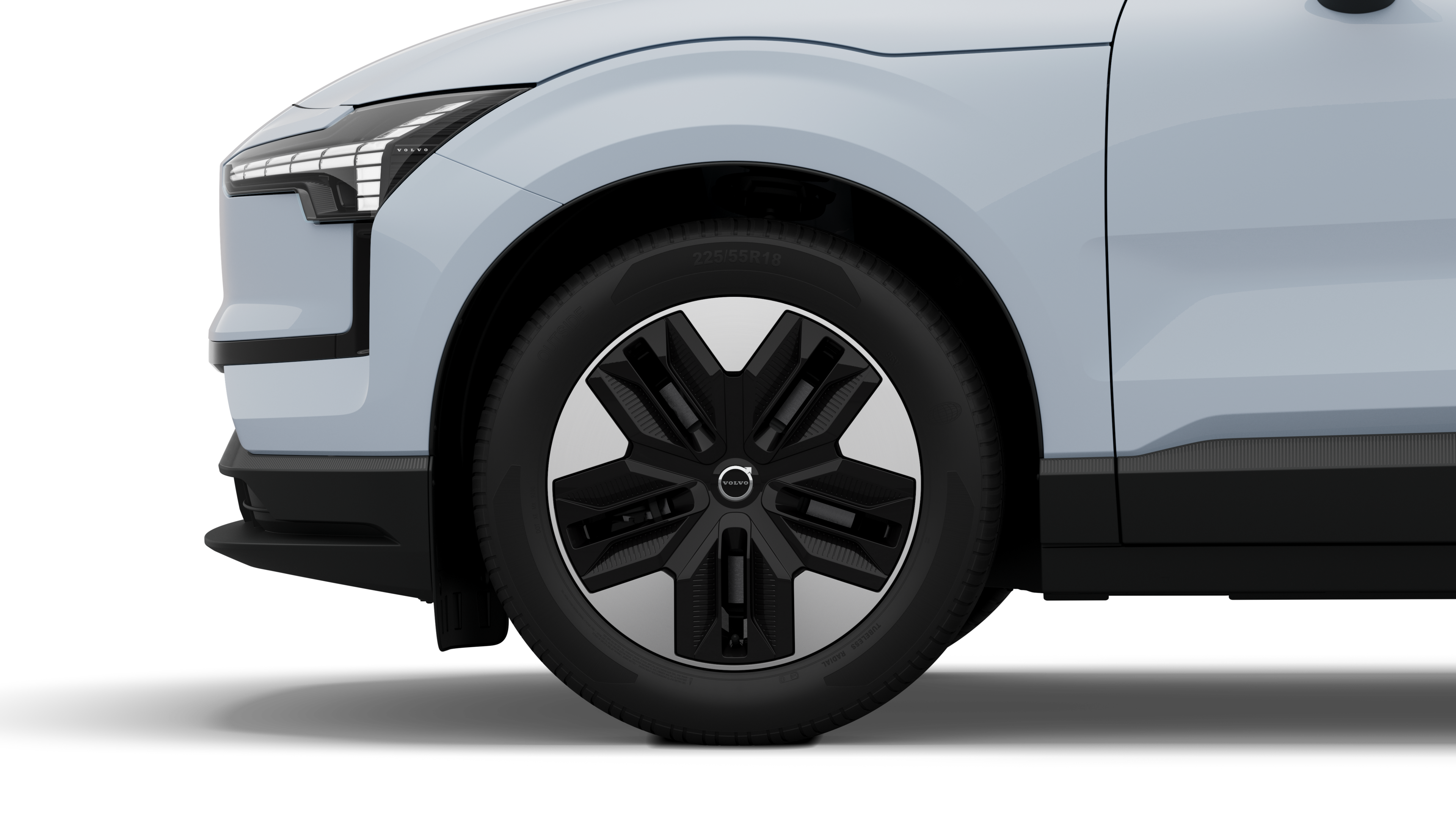 沃尔沃汽车外部侧视图聚焦于前轮和挡泥板，背景为朴素的工作室背景。