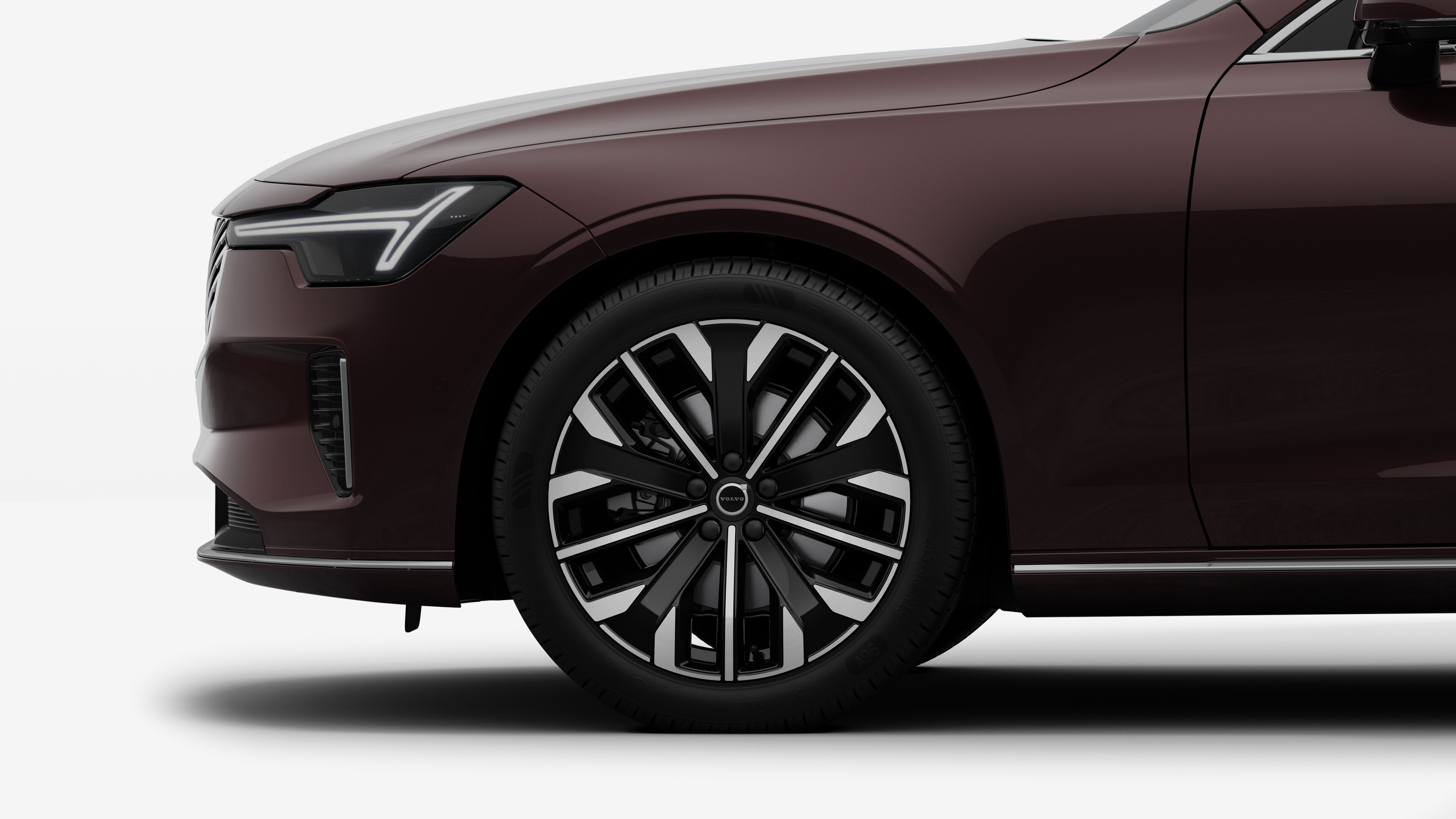 沃尔沃汽车外部侧视图聚焦于前轮和挡泥板，背景为朴素的工作室背景。