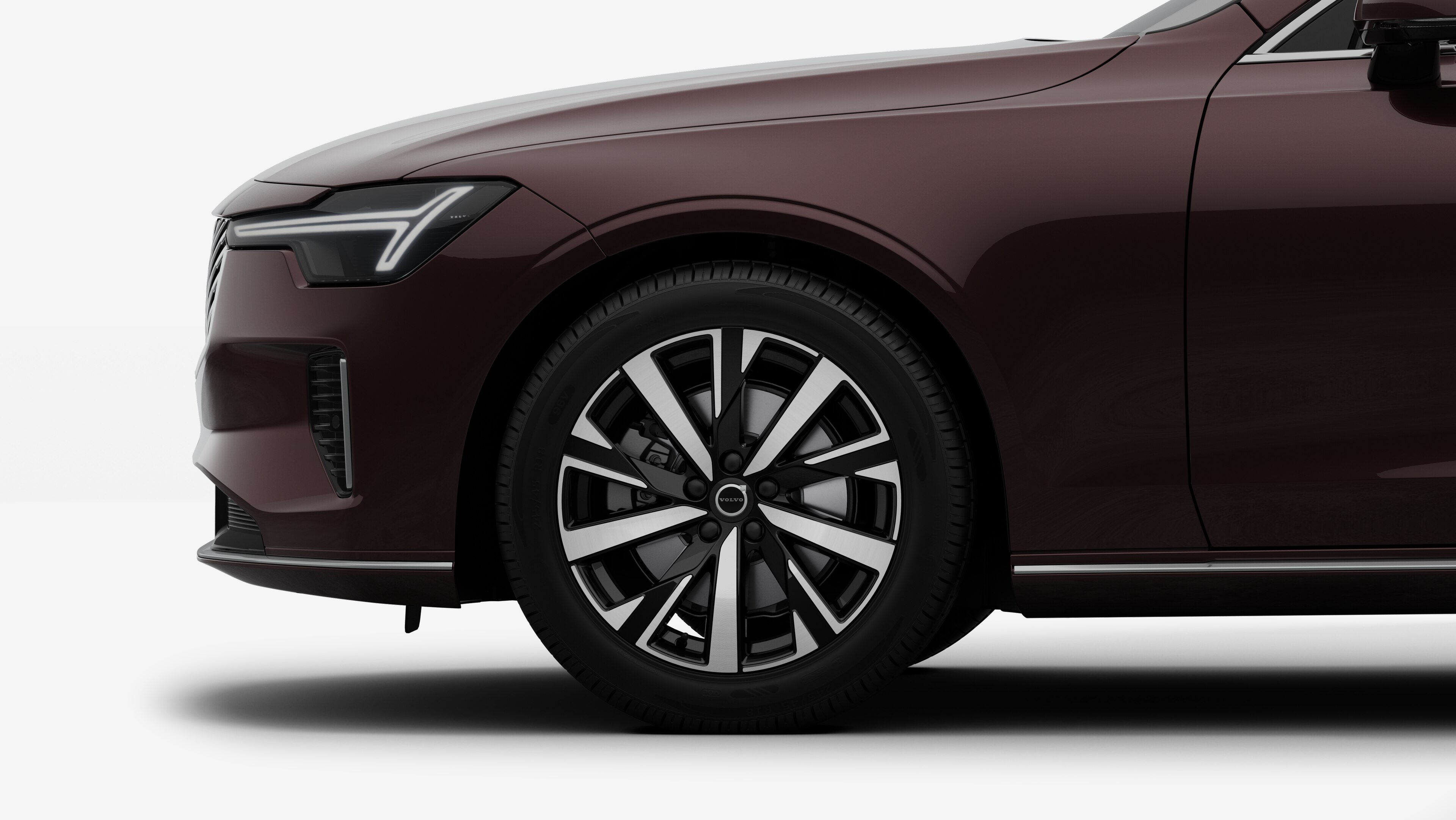 沃尔沃汽车外部侧视图聚焦于前轮和挡泥板，背景为朴素的工作室背景。