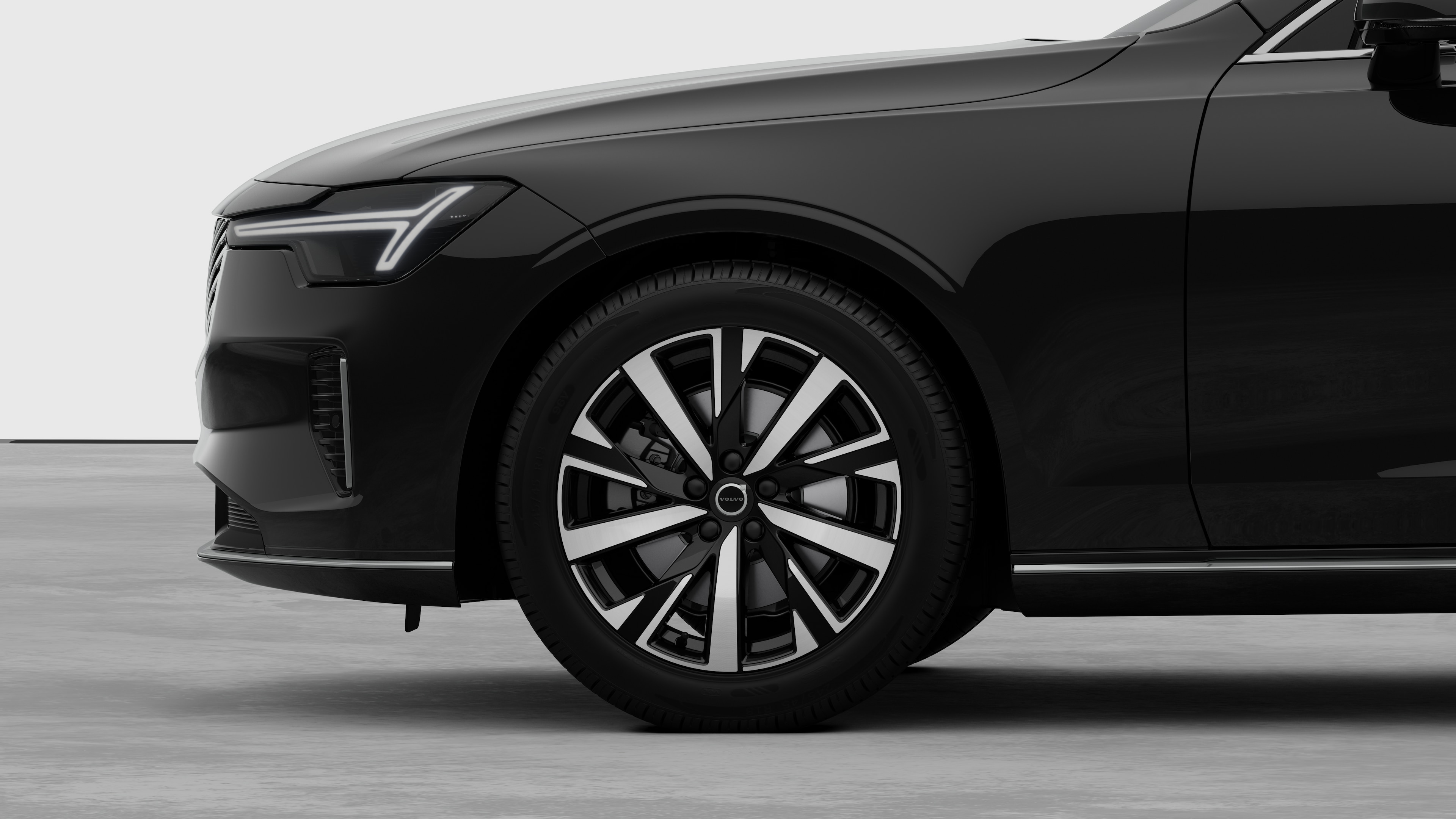 沃尔沃汽车外部侧视图聚焦于前轮和挡泥板，背景为朴素的工作室背景。