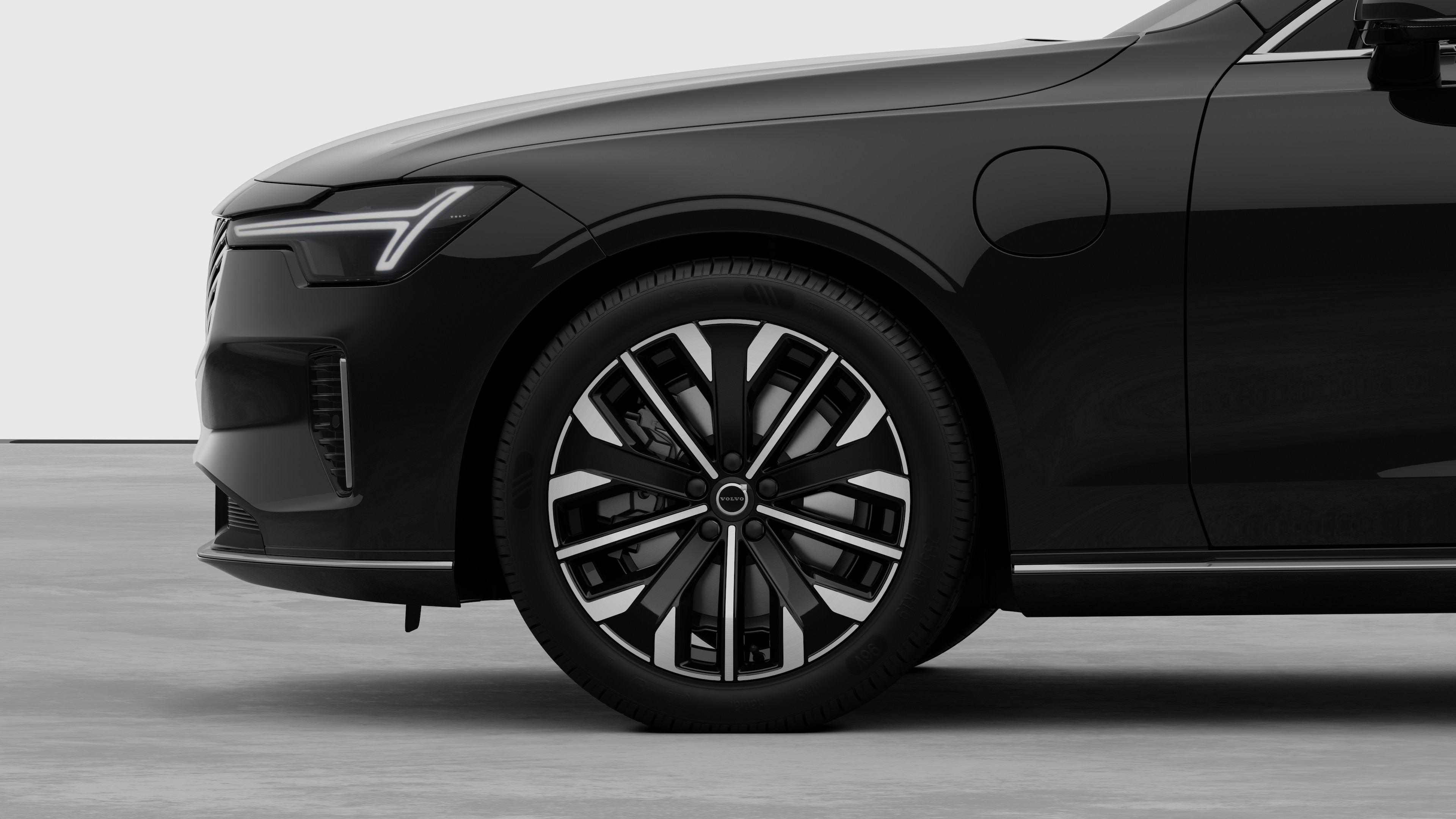 沃尔沃汽车外部侧视图聚焦于前轮和挡泥板，背景为朴素的工作室背景。