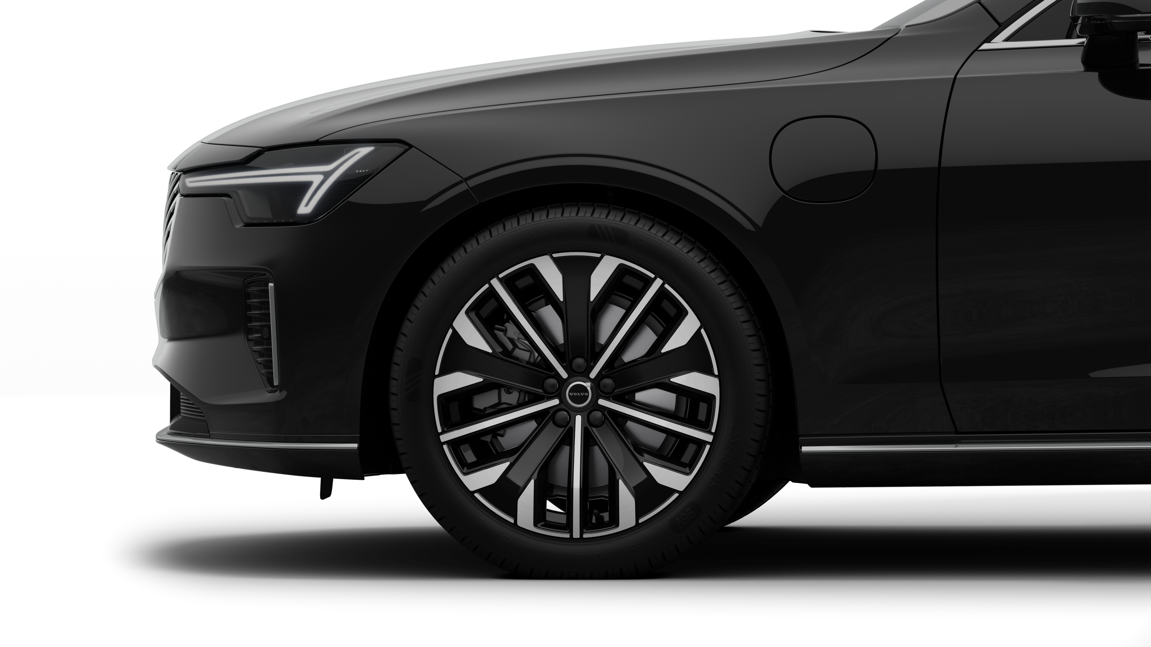 沃尔沃汽车外部侧视图聚焦于前轮和挡泥板，背景为朴素的工作室背景。