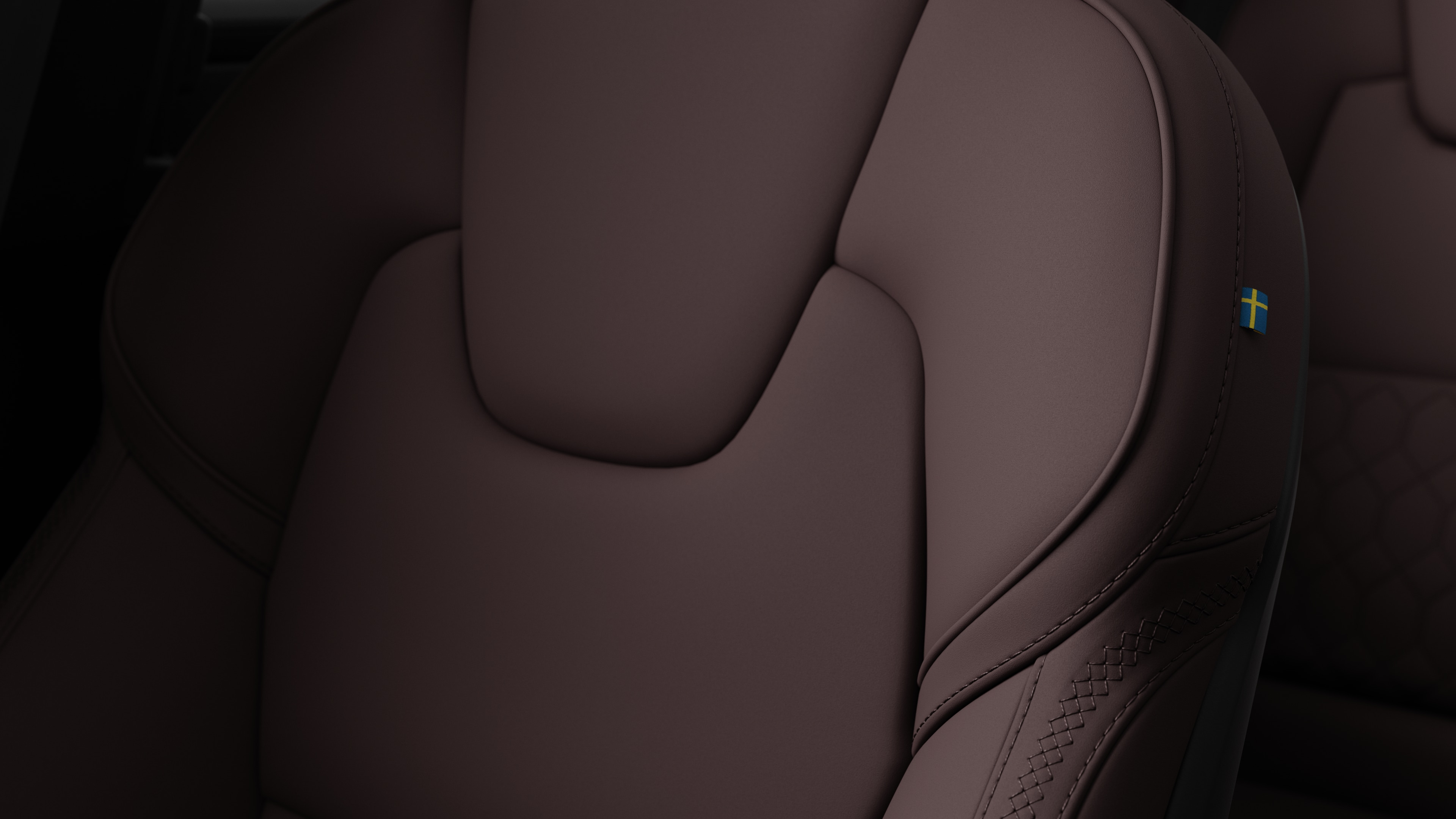 沃尔沃汽车内部座椅细节的特写，显示缝线和瑞典小旗牌。