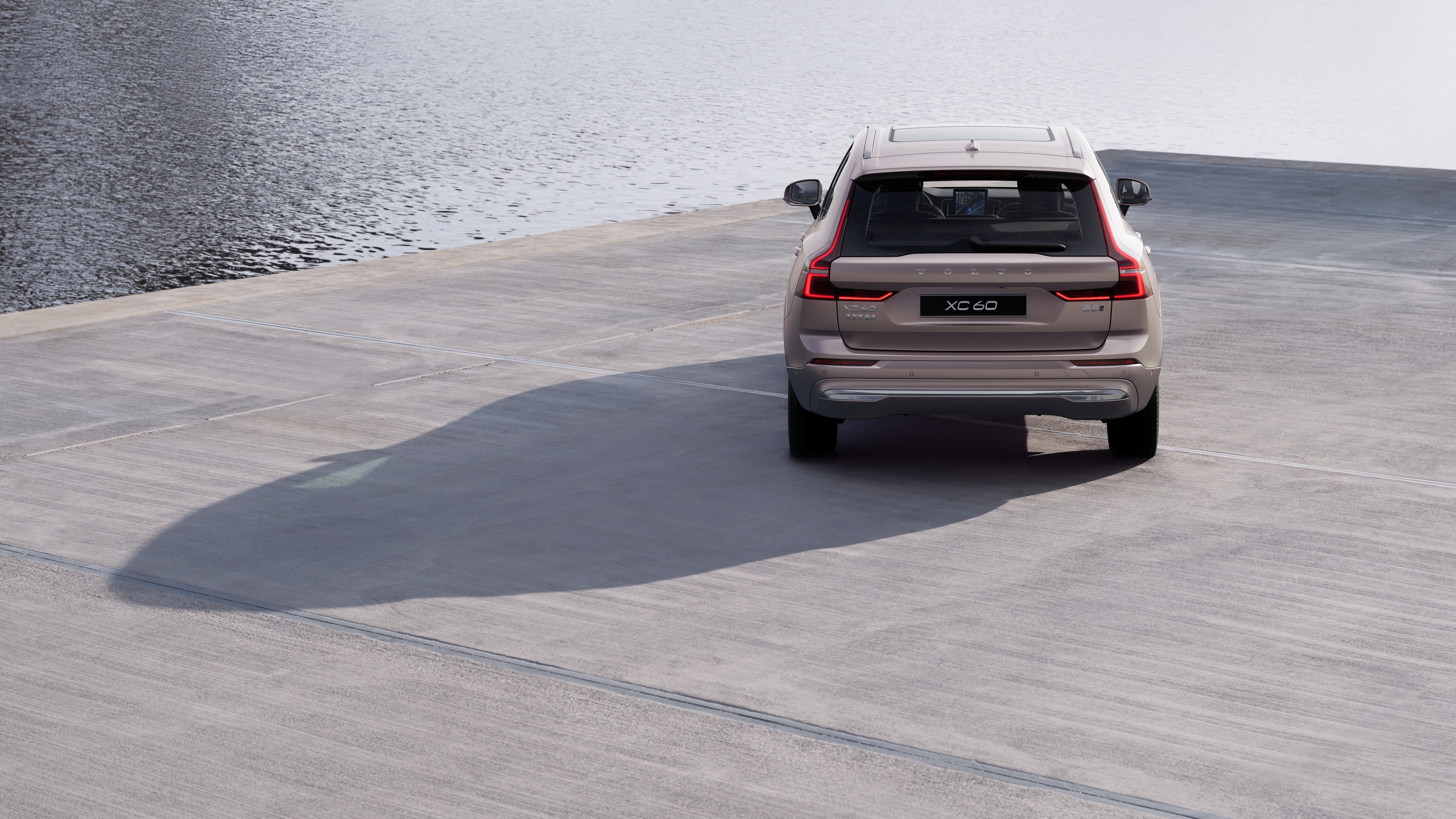 沃尔沃汽车后视图在蜿蜒的沿海道路上，以海滨为背景。