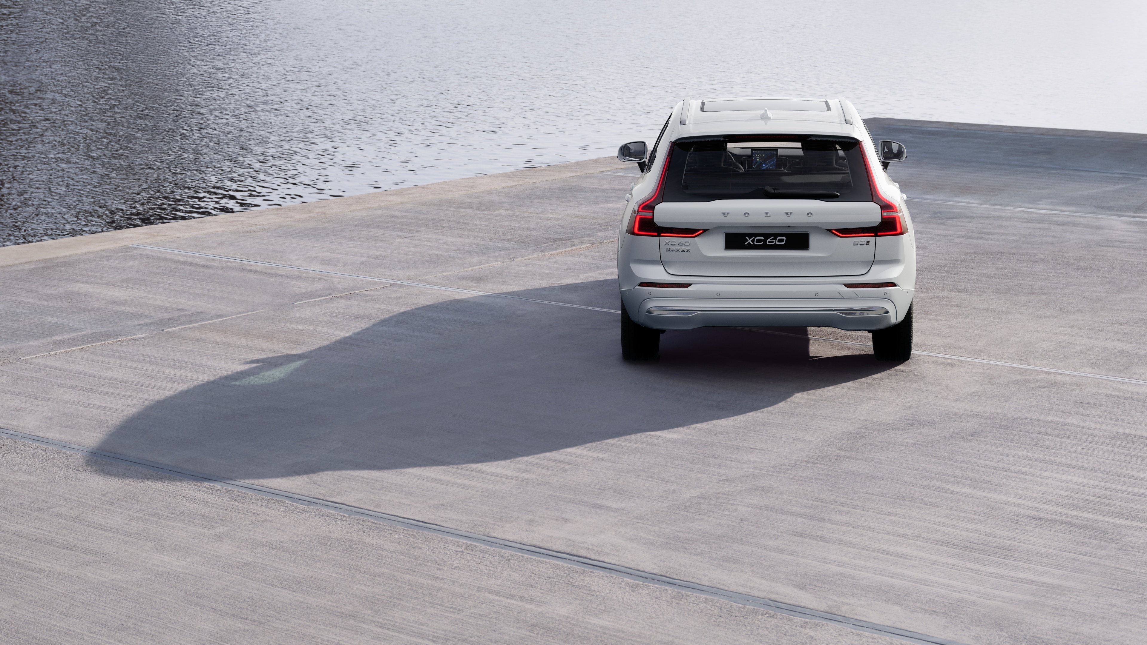 沃尔沃汽车后视图在蜿蜒的沿海道路上，以海滨为背景。