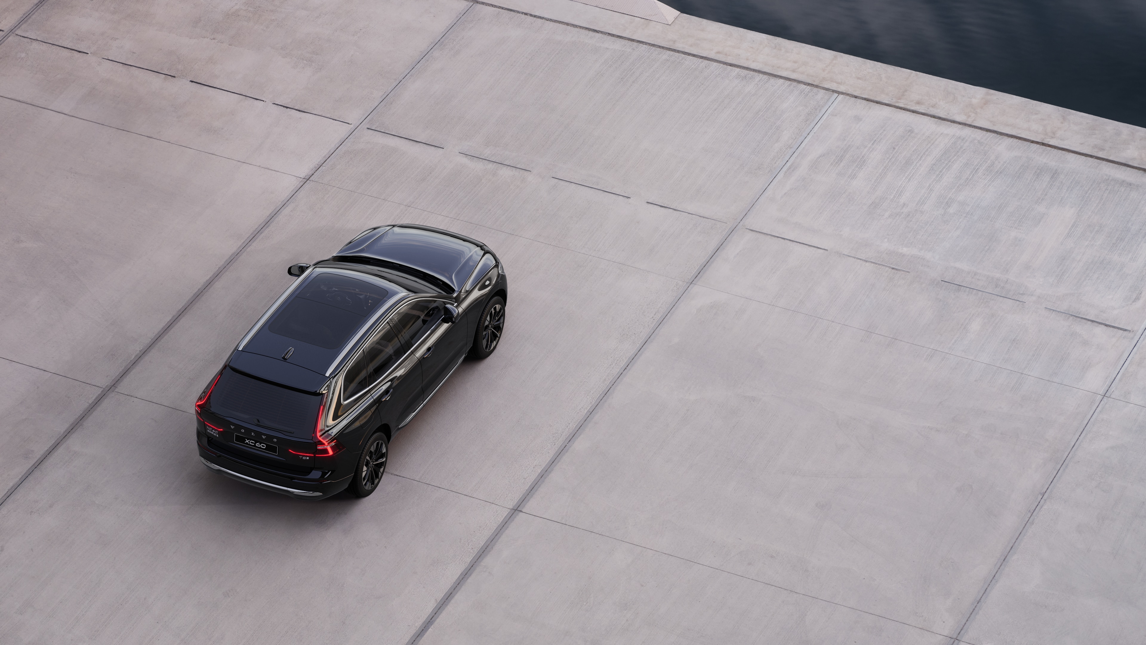 沃尔沃汽车后视图停在安静的水边街道上,以铺好的走道和水为背景。