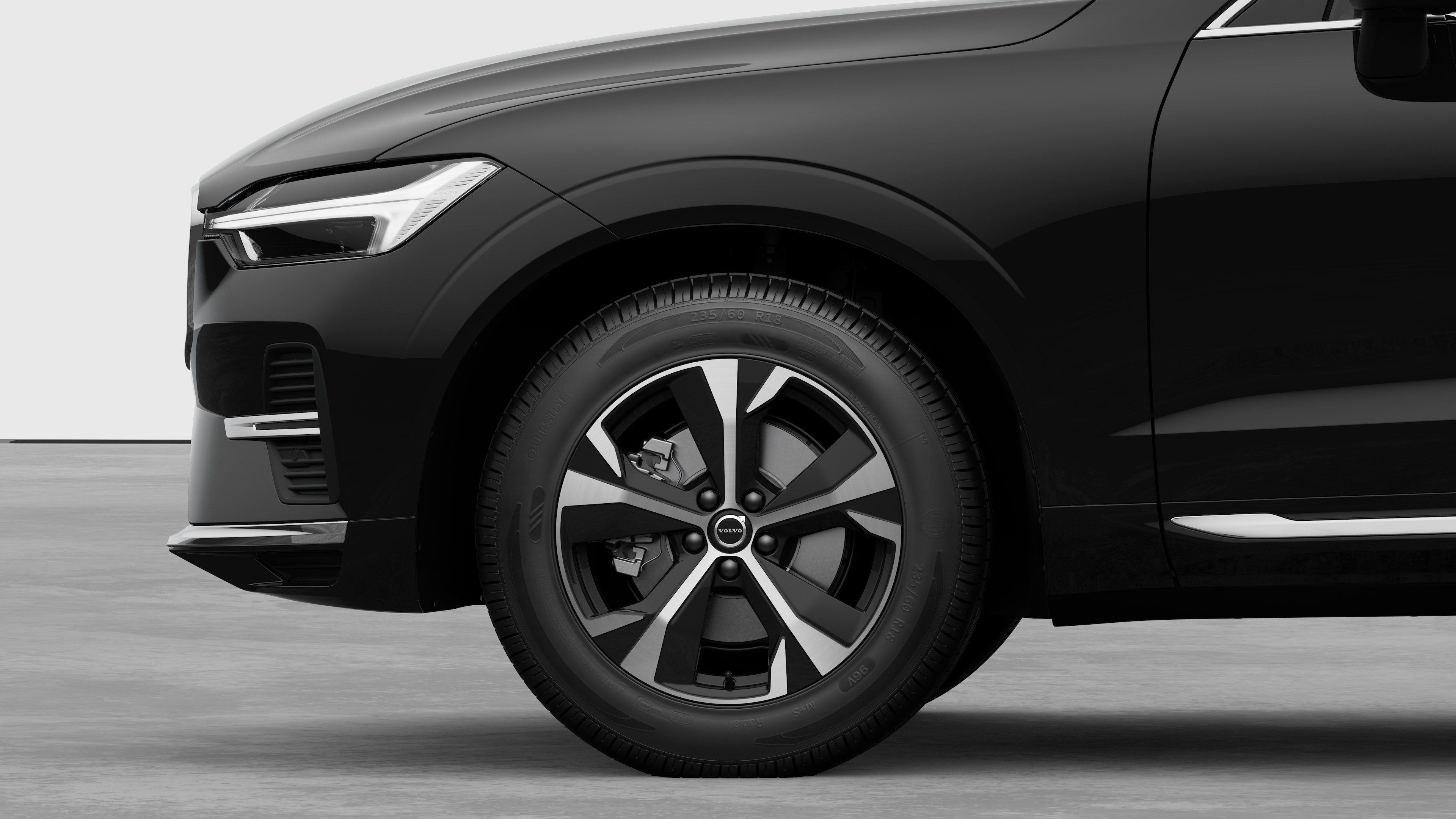 沃尔沃汽车外部侧视图聚焦于前轮和挡泥板，背景为朴素的工作室背景。