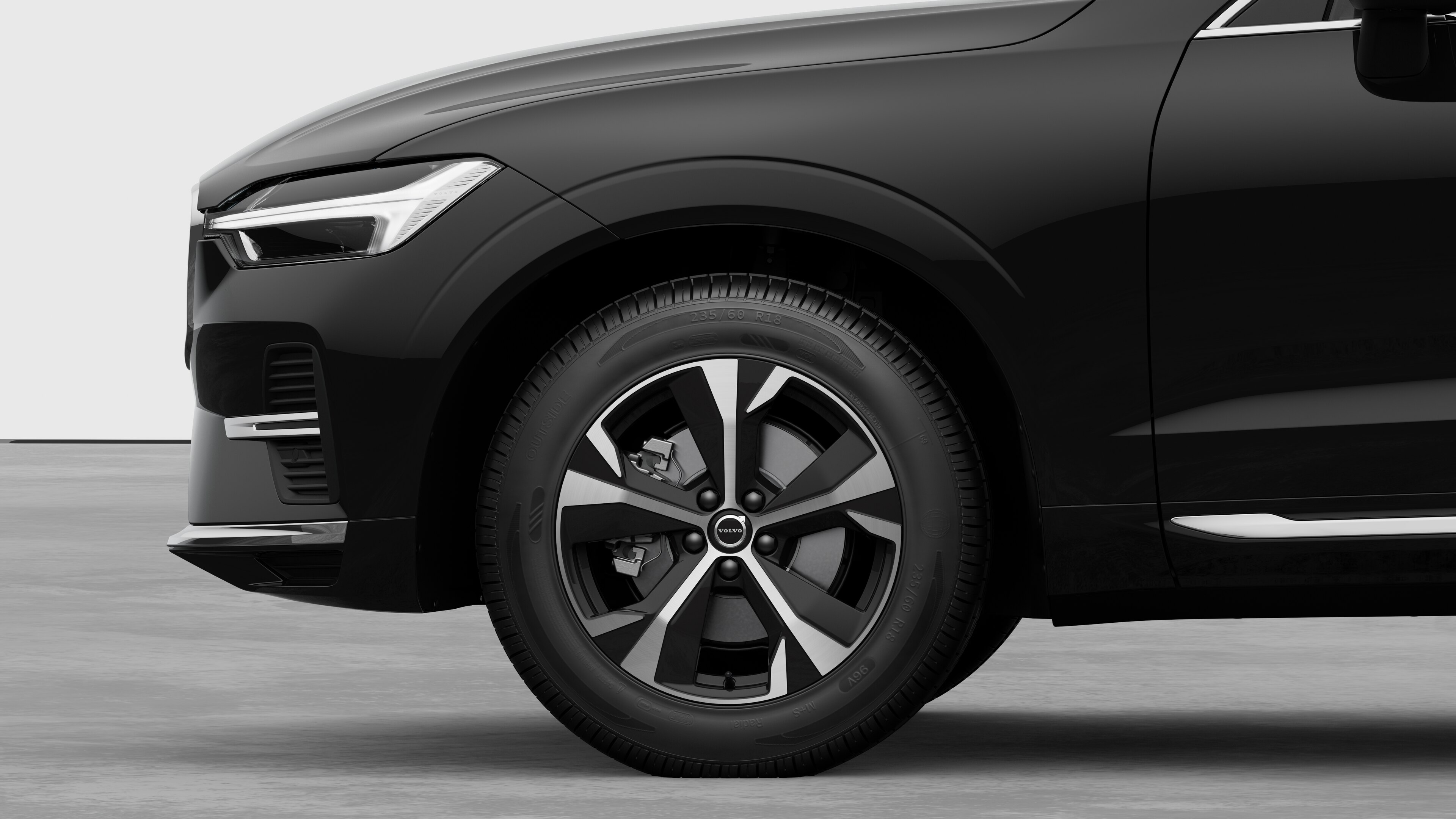 沃尔沃汽车外部侧视图聚焦于前轮和挡泥板，背景为朴素的工作室背景。