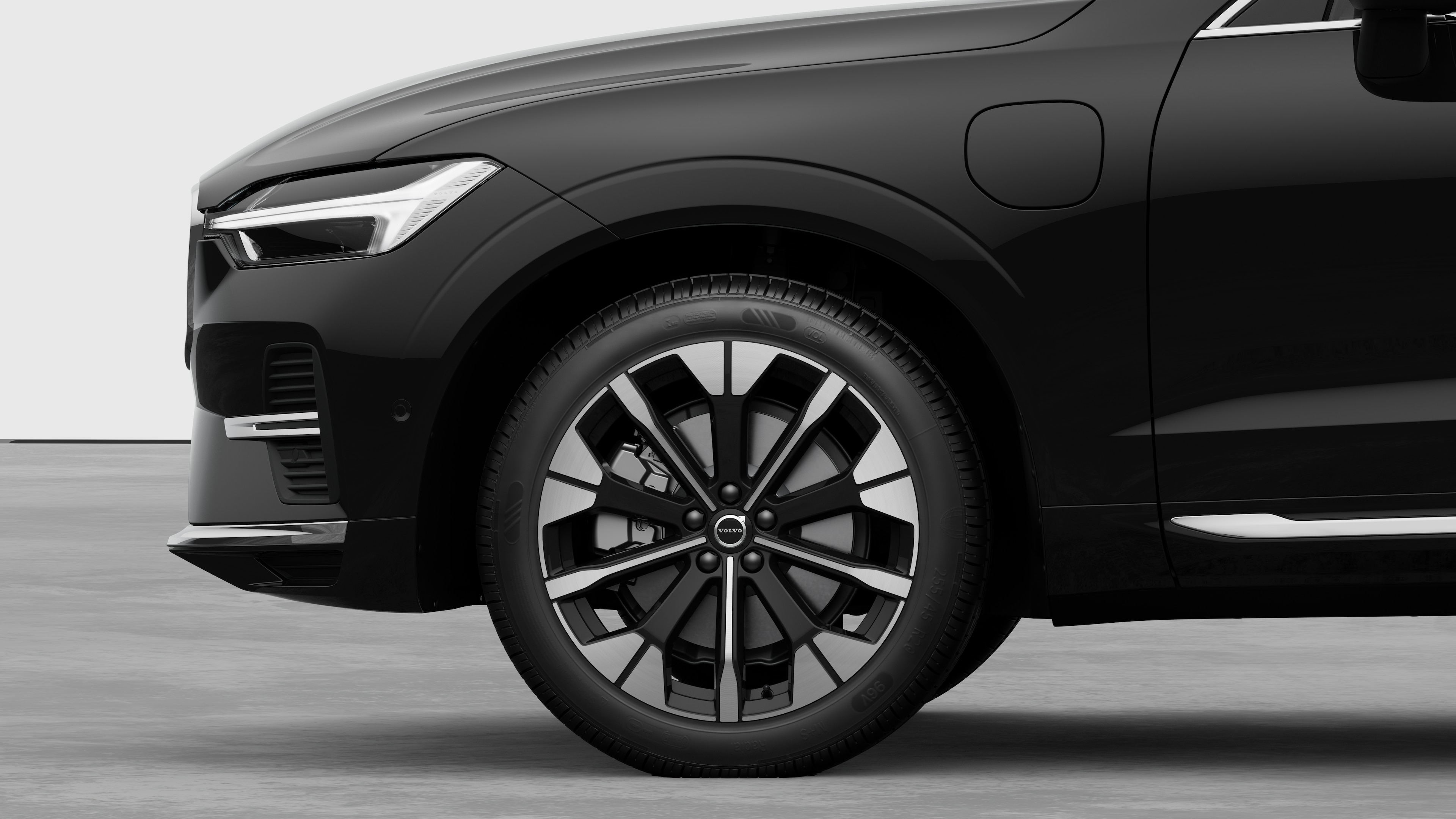 沃尔沃汽车外部侧视图聚焦于前轮和挡泥板，背景为朴素的工作室背景。