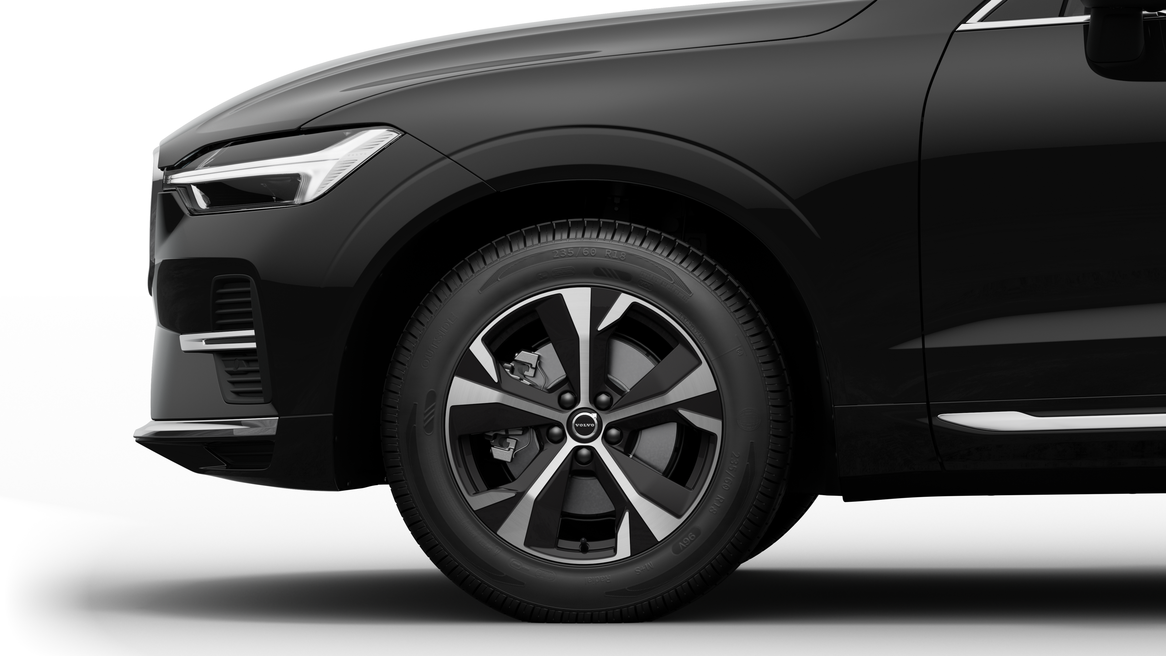 沃尔沃汽车外部侧视图聚焦于前轮和挡泥板，背景为朴素的工作室背景。