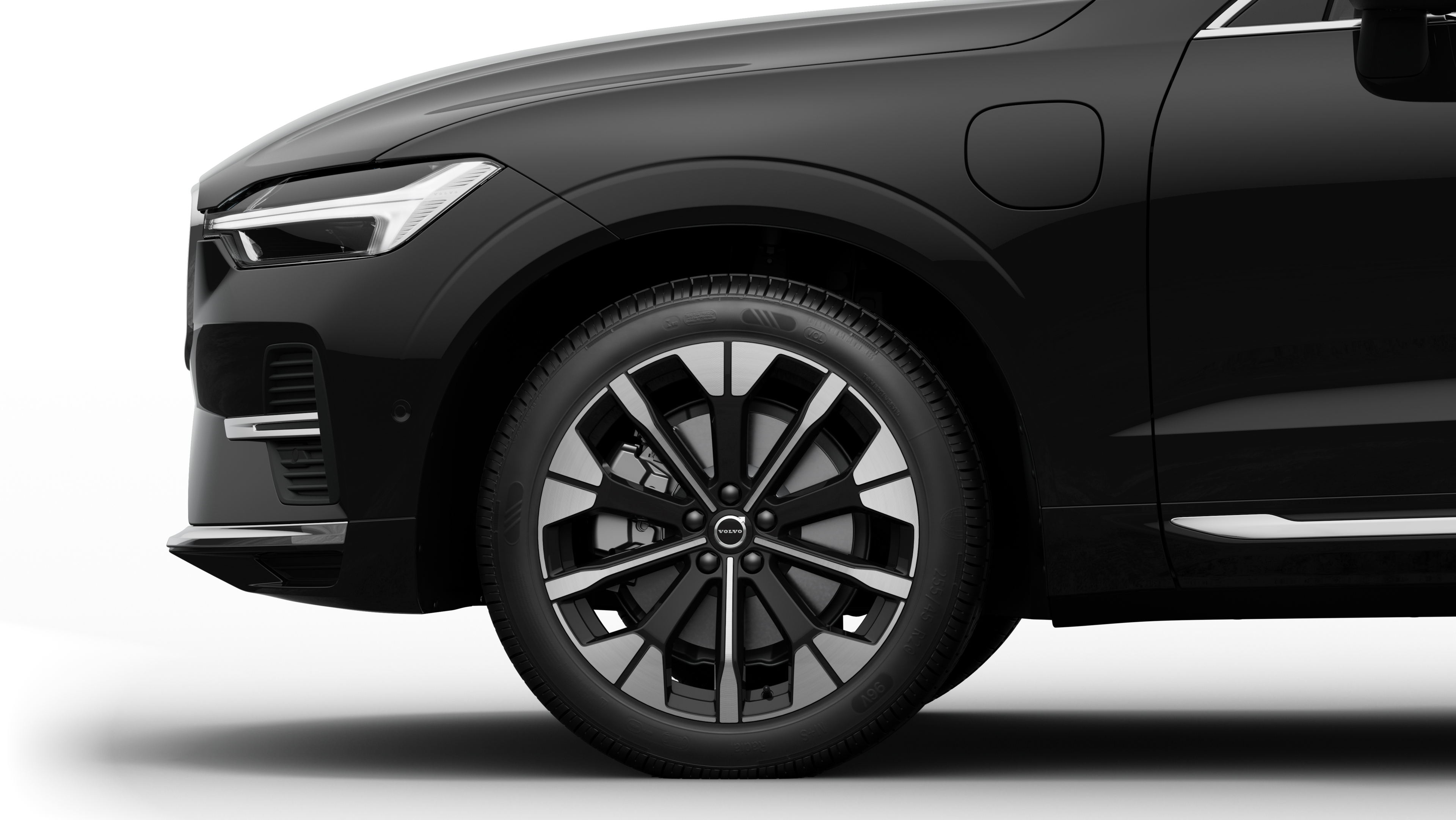 沃尔沃汽车外部侧视图聚焦于前轮和挡泥板，背景为朴素的工作室背景。