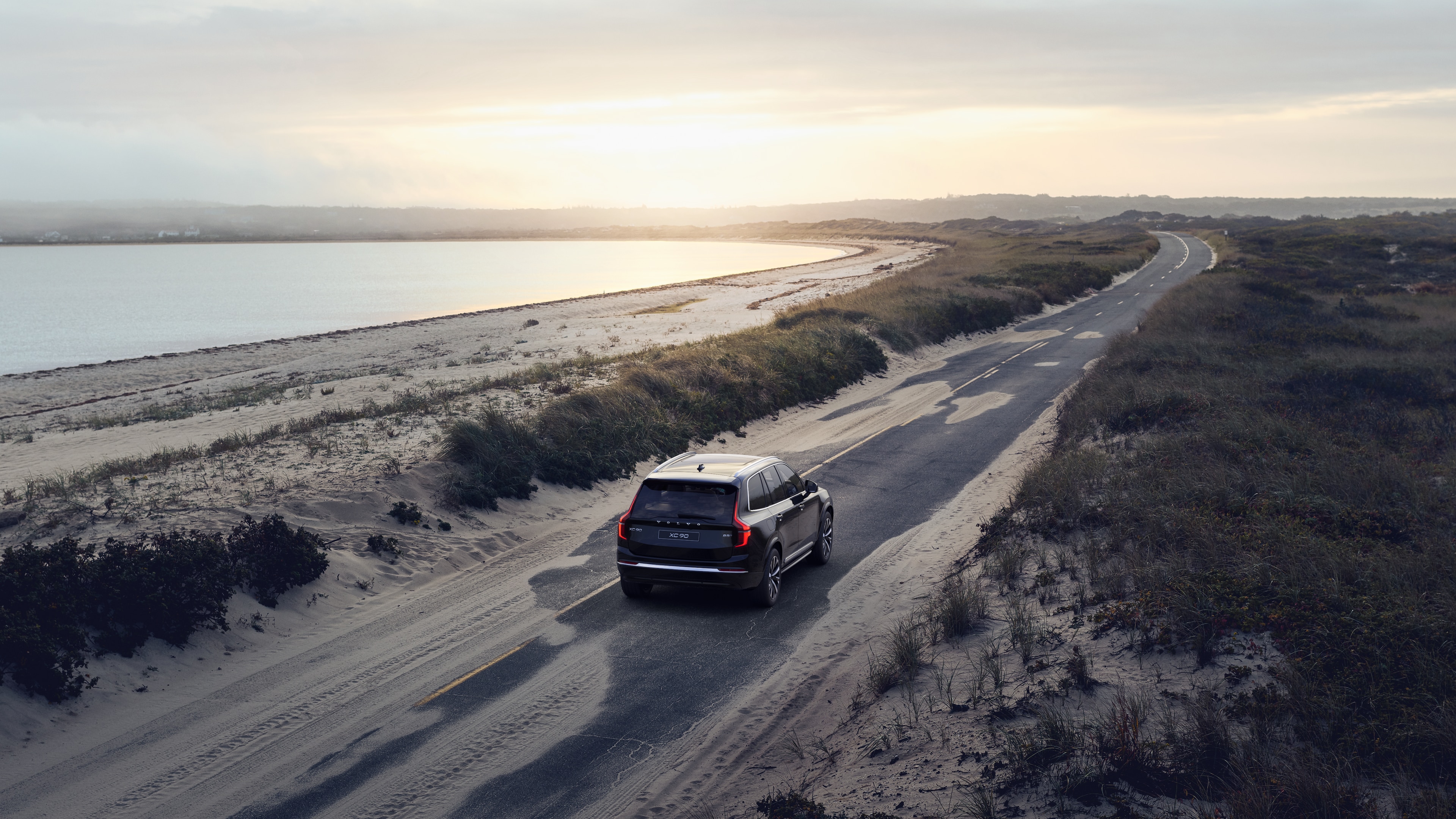 沃尔沃汽车后视图在蜿蜒的沿海道路上，以海滨为背景。