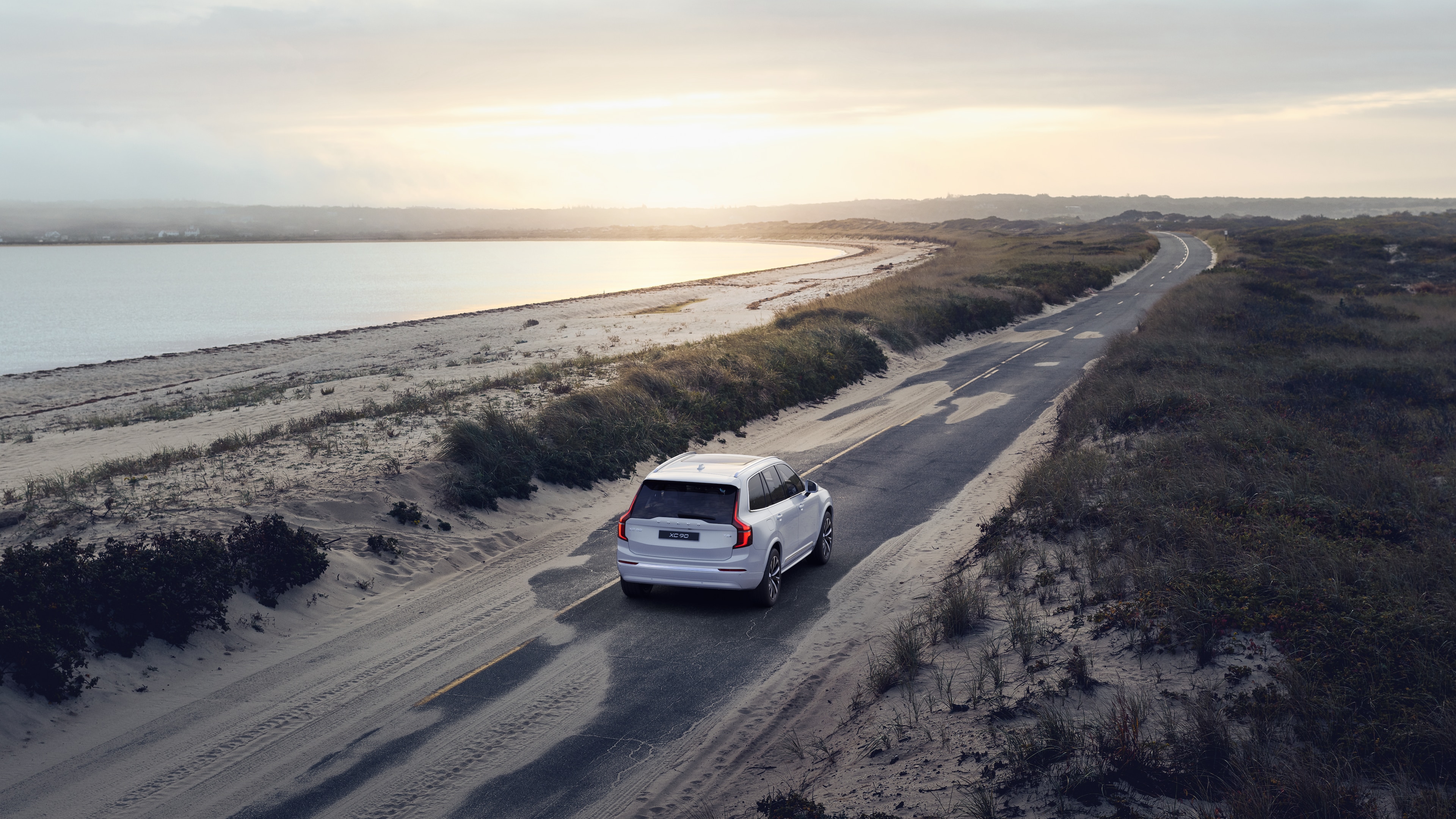 沃尔沃汽车后视图在蜿蜒的沿海道路上，以海滨为背景。