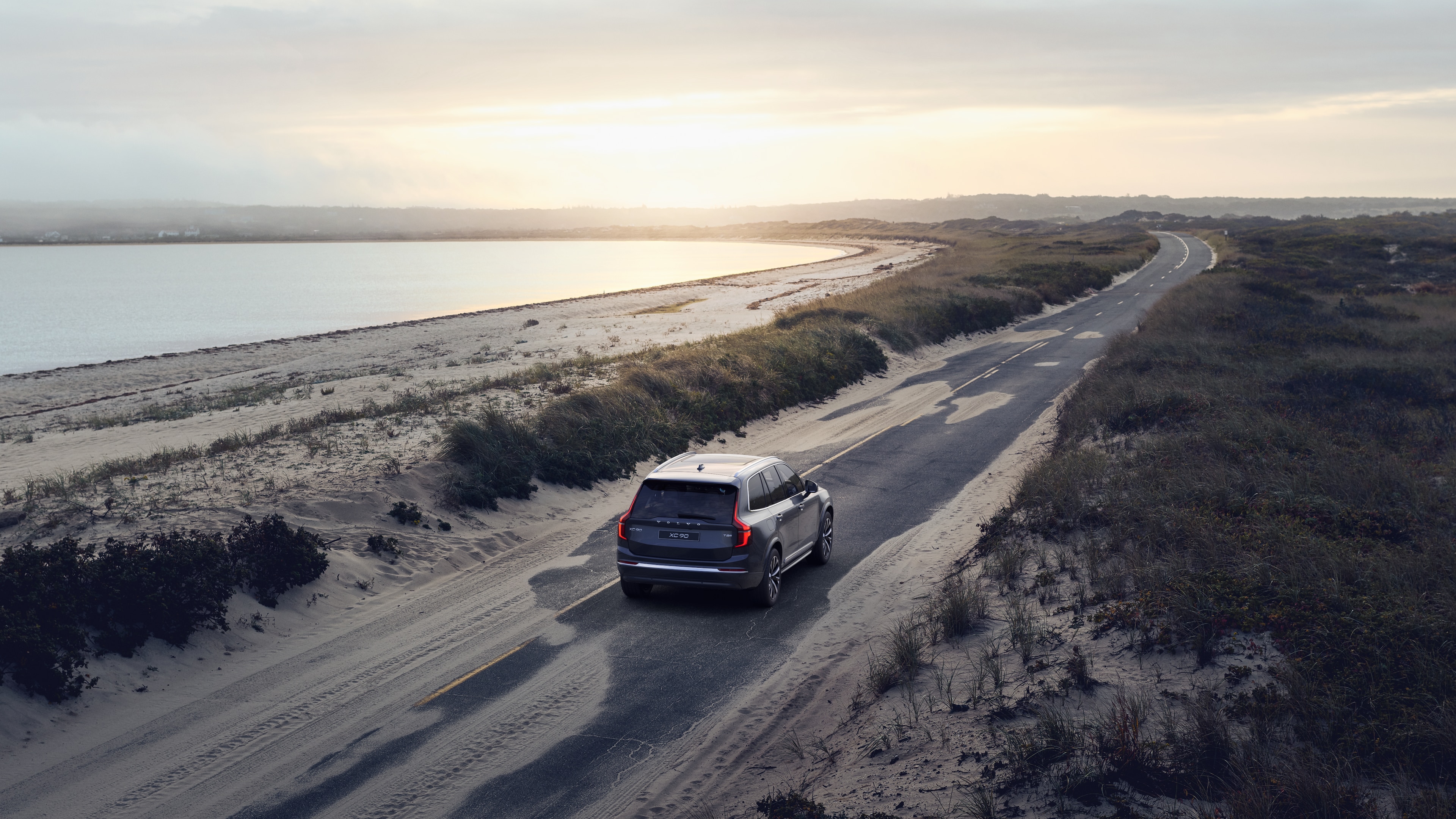 沃尔沃汽车后视图在蜿蜒的沿海道路上，以海滨为背景。