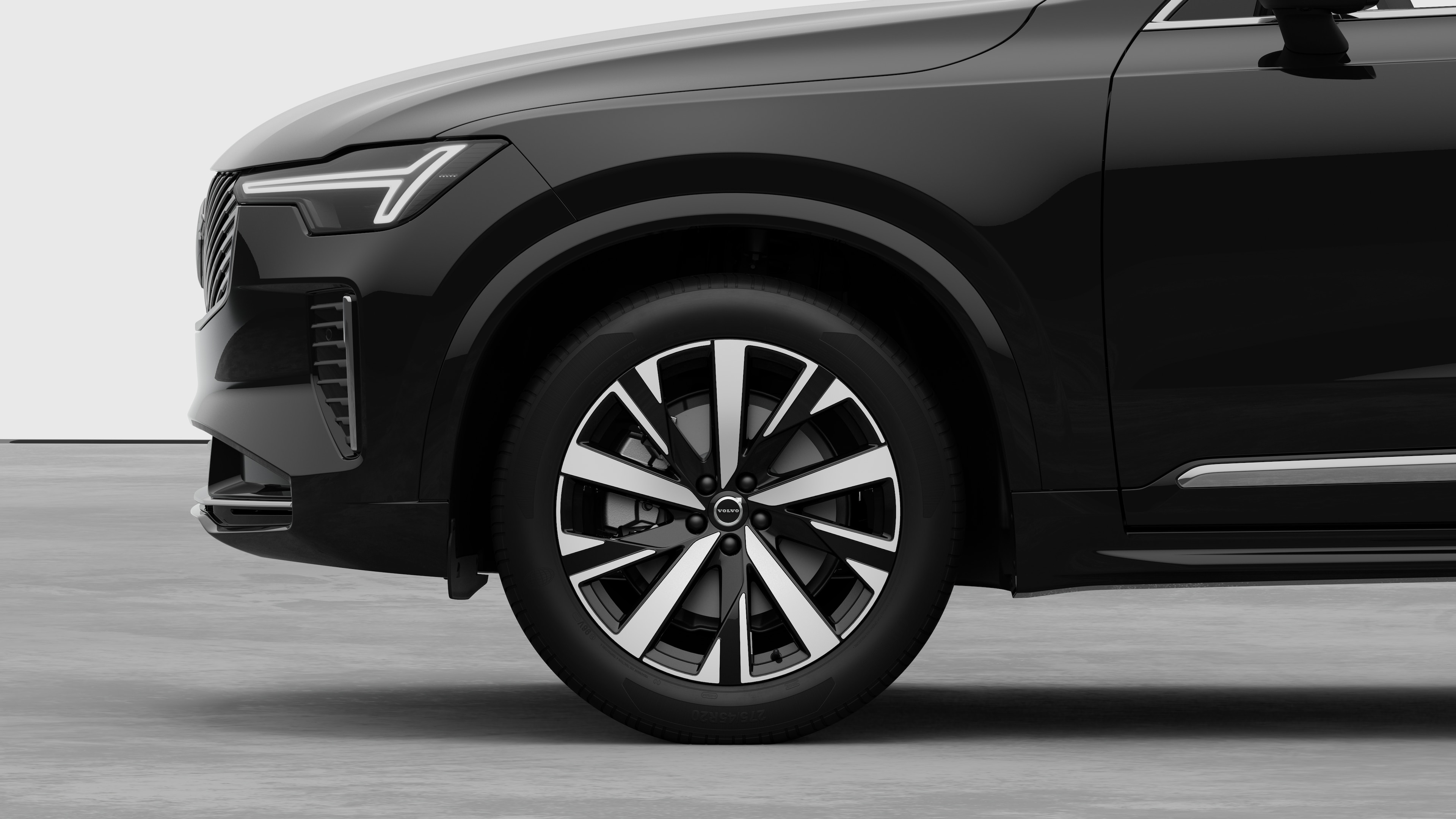 沃尔沃汽车外部侧视图聚焦于前轮和挡泥板，背景为朴素的工作室背景。