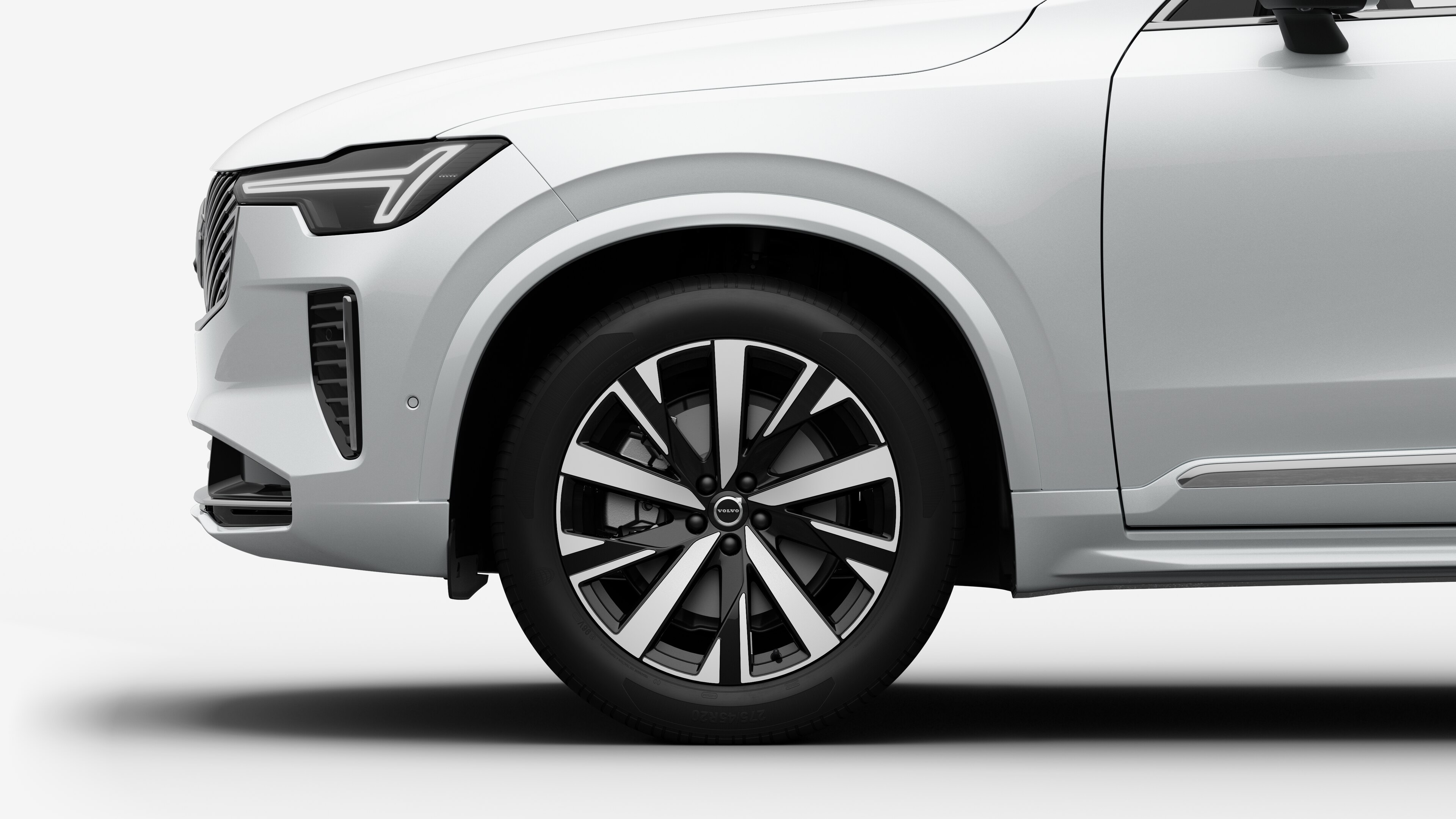沃尔沃汽车外部侧视图聚焦于前轮和挡泥板，背景为朴素的工作室背景。