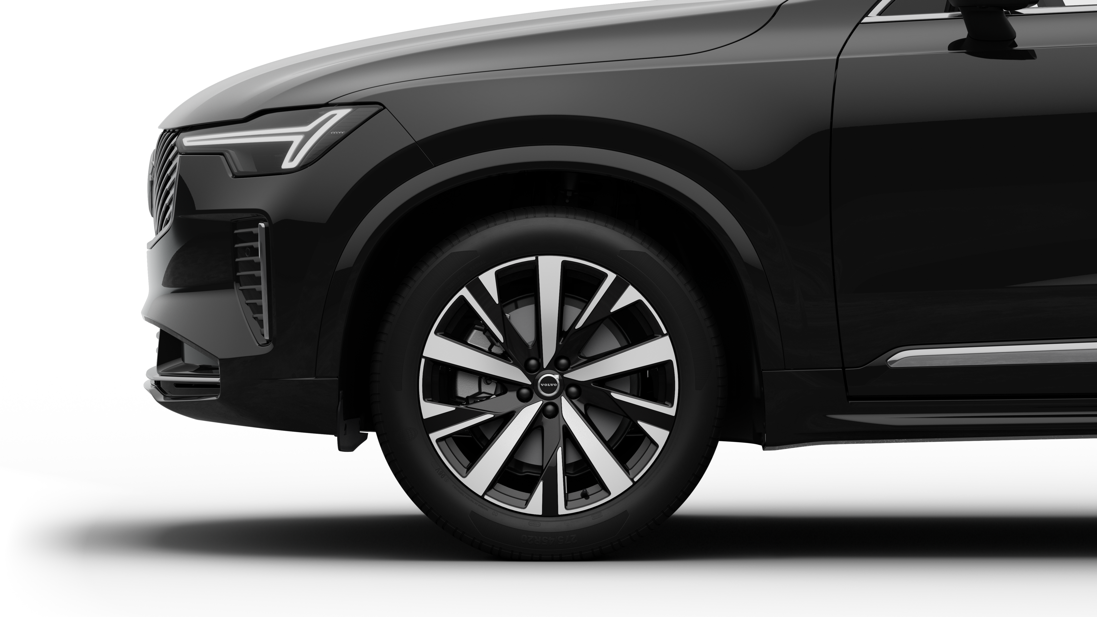 沃尔沃汽车外部侧视图聚焦于前轮和挡泥板，背景为朴素的工作室背景。