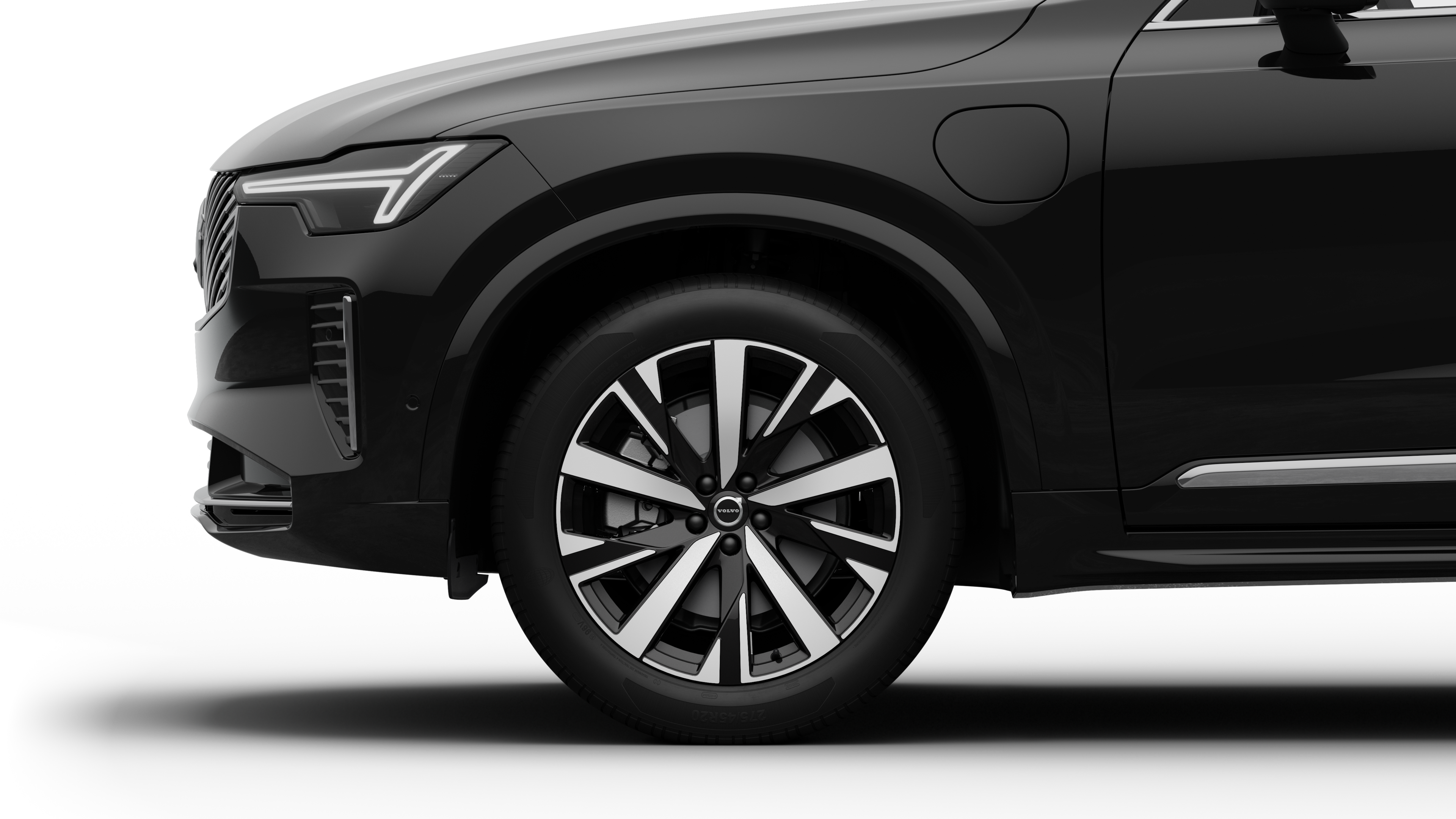 沃尔沃汽车外部侧视图聚焦于前轮和挡泥板，背景为朴素的工作室背景。