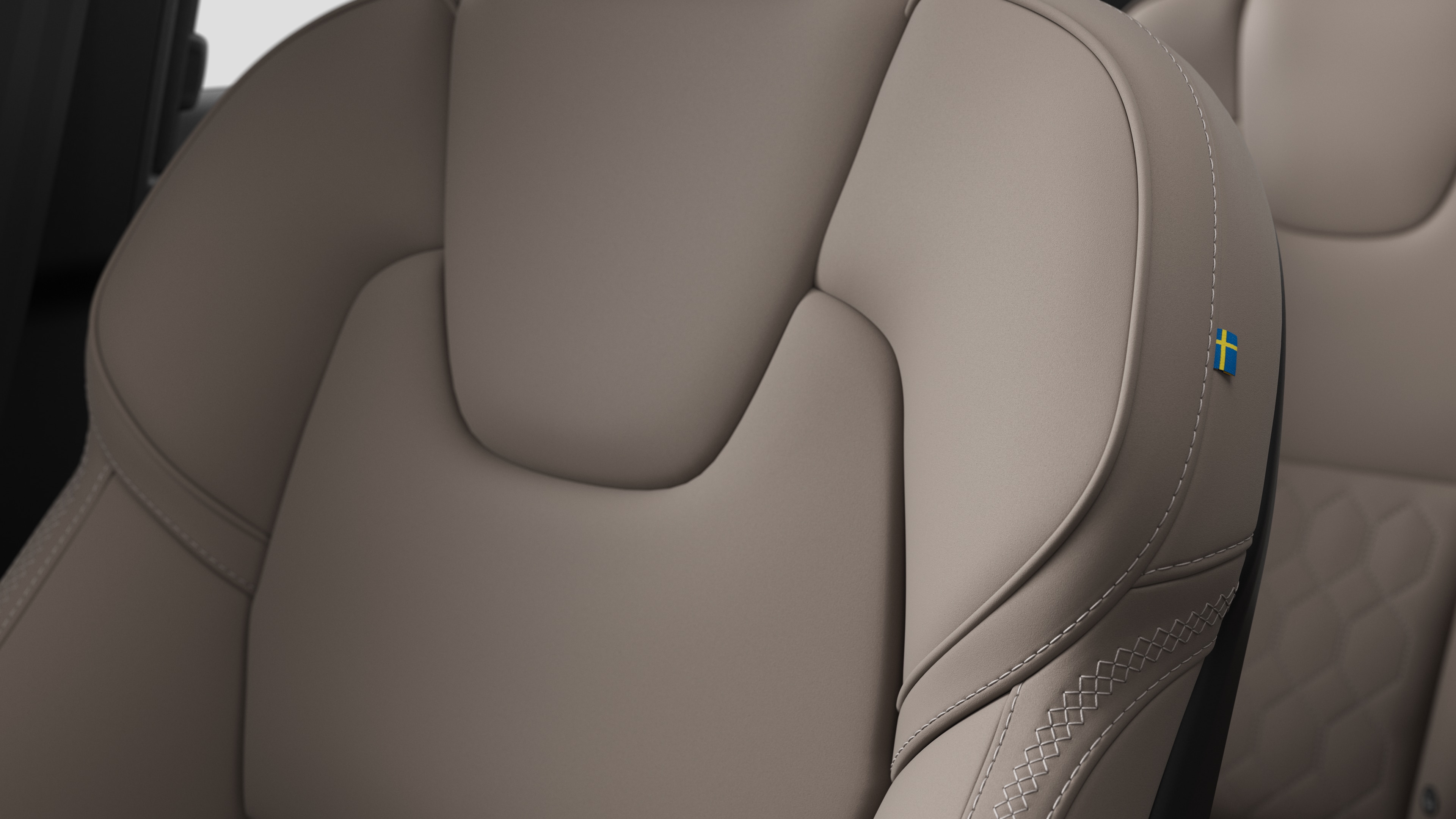 沃尔沃汽车内部座椅细节的特写，显示缝线和瑞典小旗牌。