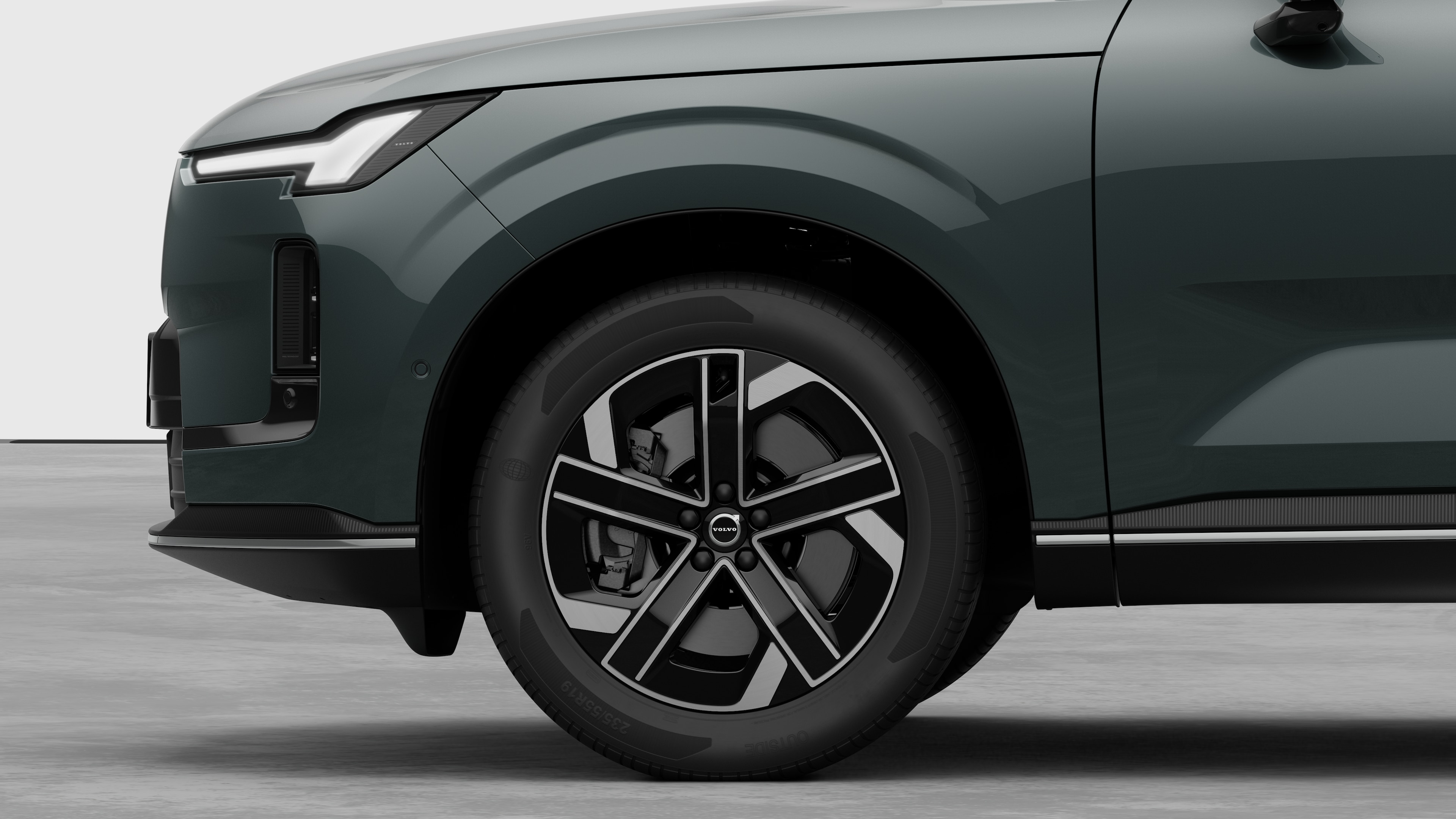 沃尔沃汽车外部侧视图聚焦于前轮和挡泥板，背景为朴素的工作室背景。