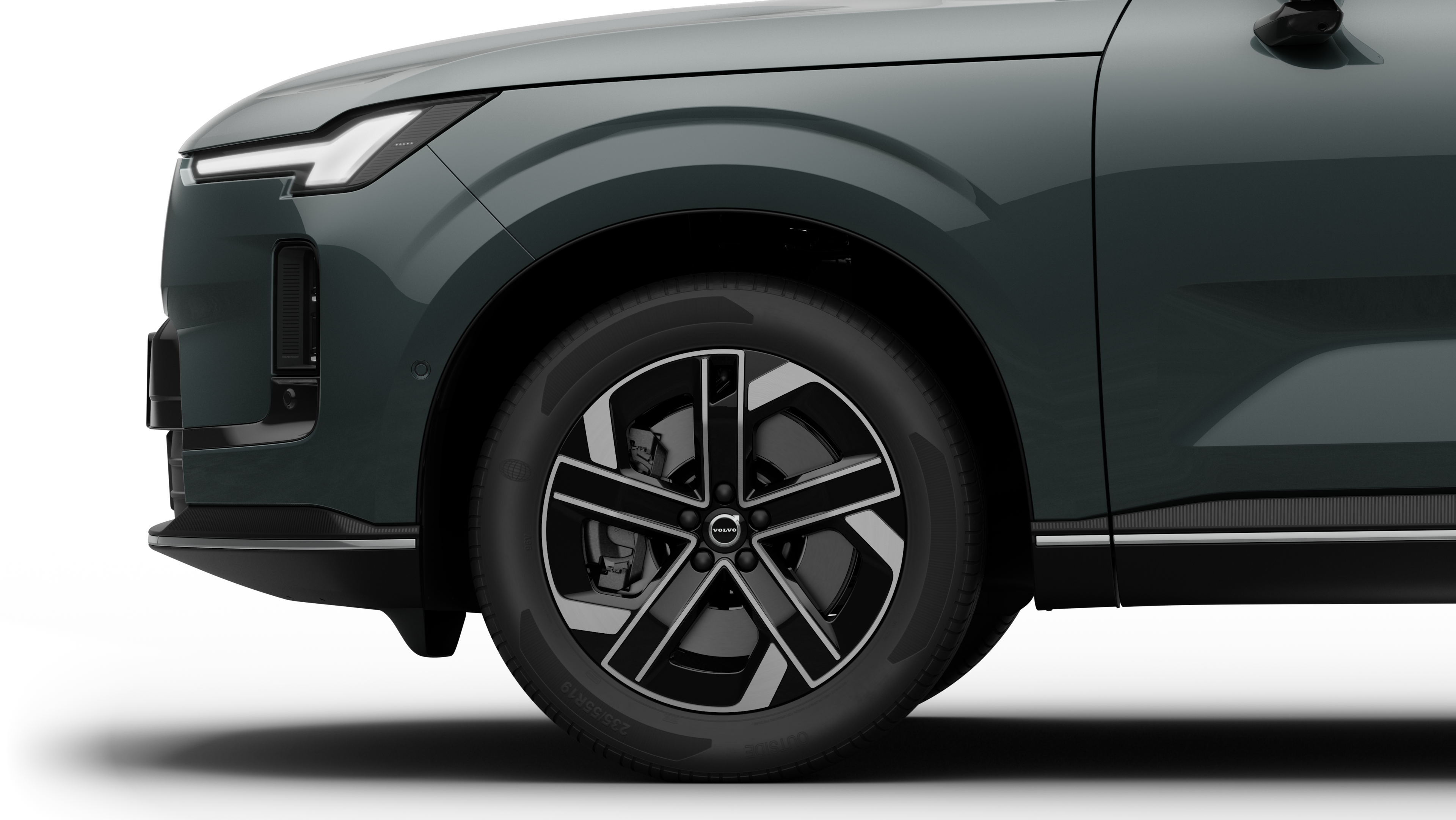 沃尔沃汽车外部侧视图聚焦于前轮和挡泥板，背景为朴素的工作室背景。