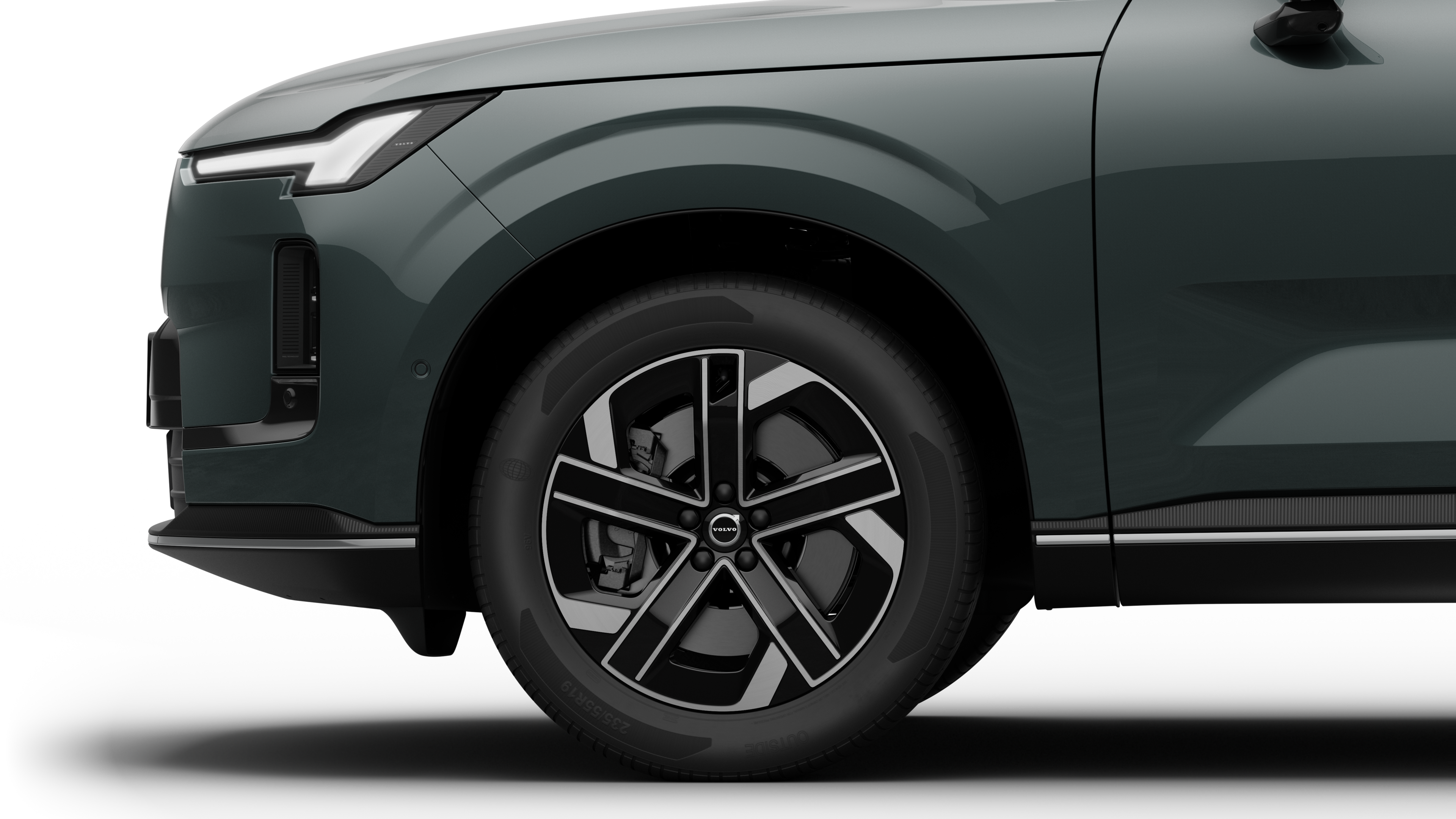 沃尔沃汽车外部侧视图聚焦于前轮和挡泥板，背景为朴素的工作室背景。