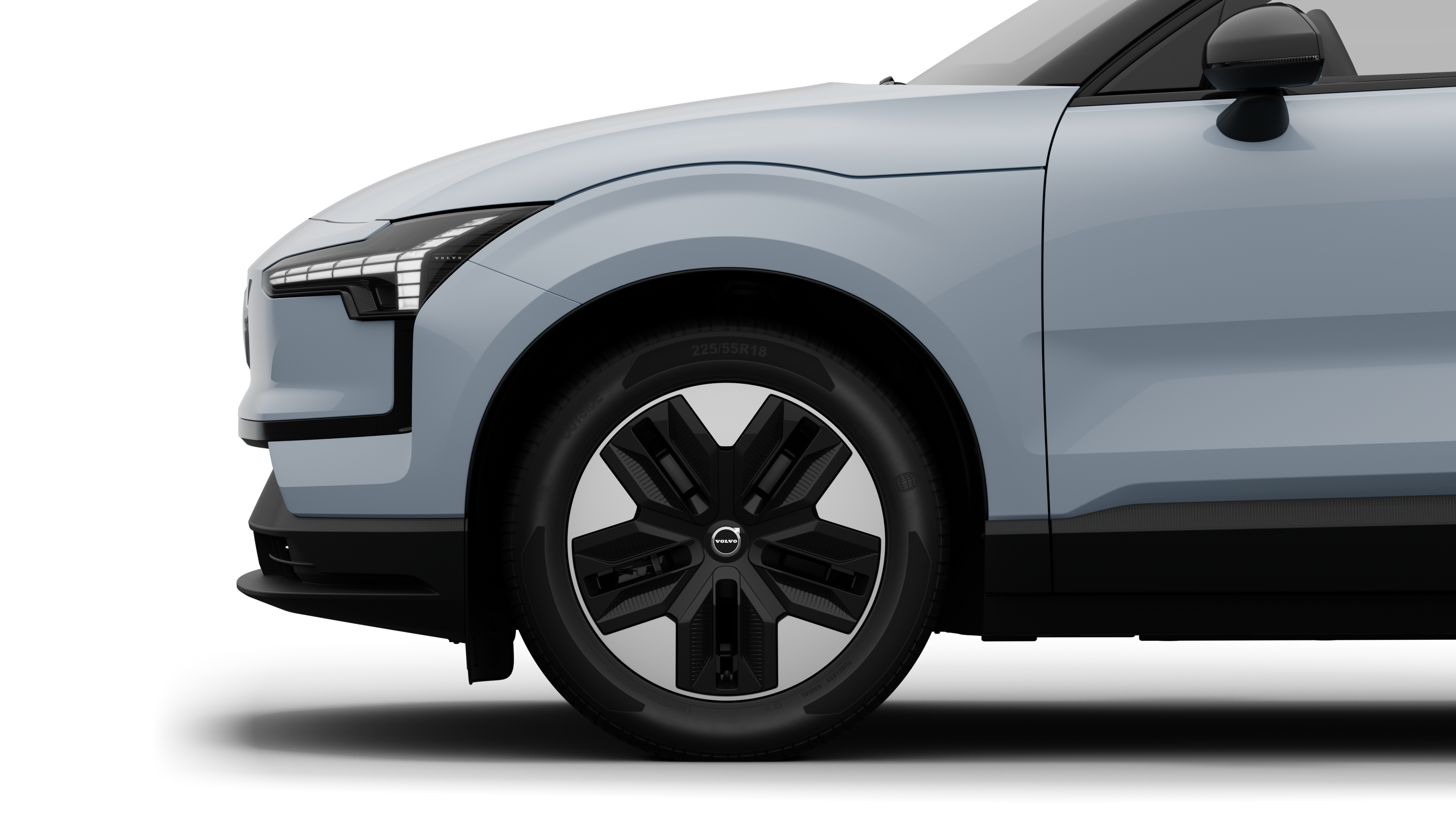 沃尔沃汽车外部侧视图聚焦于前轮和挡泥板，背景为朴素的工作室背景。