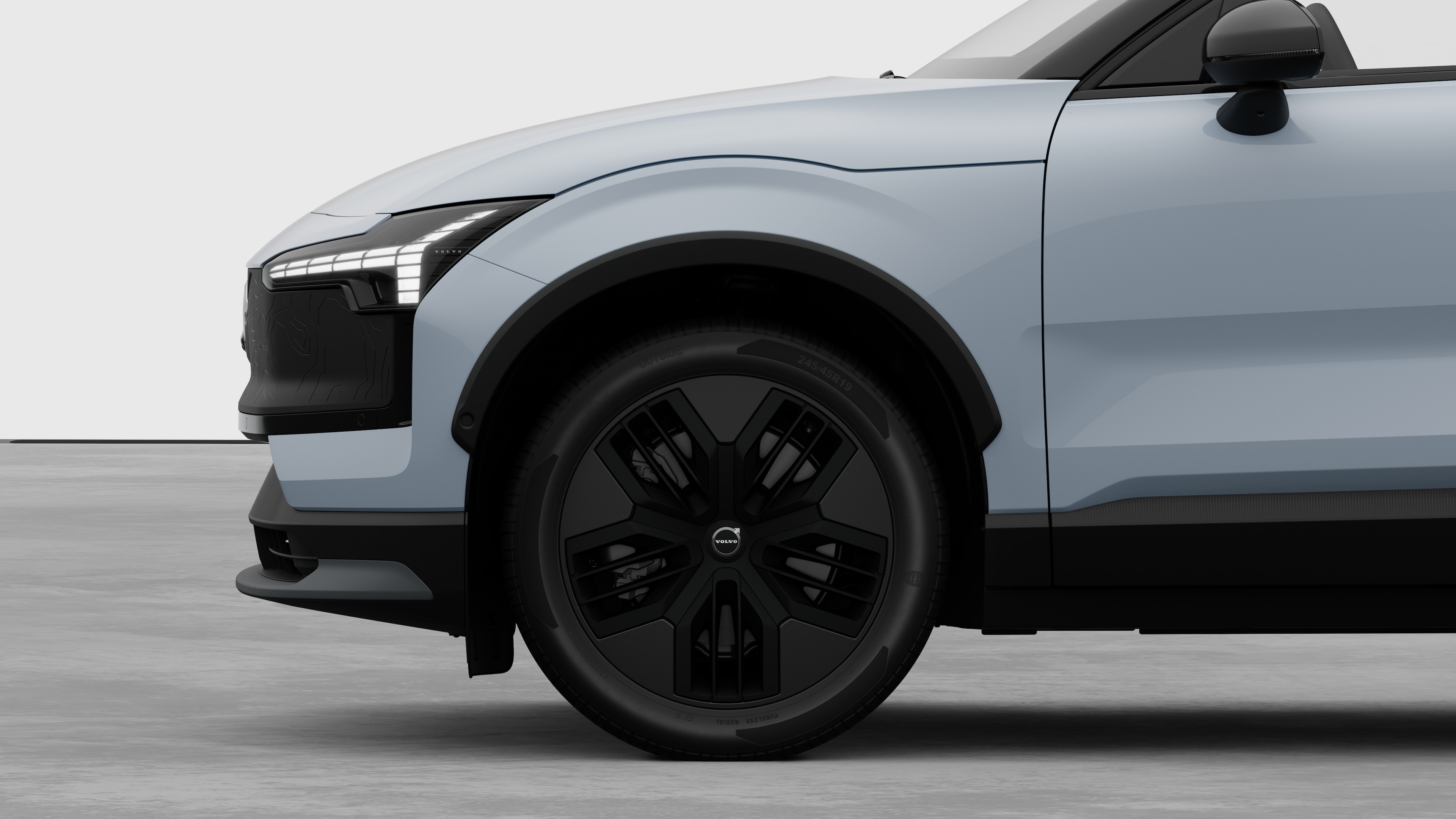 沃尔沃汽车外部侧视图聚焦于前轮和挡泥板，背景为朴素的工作室背景。