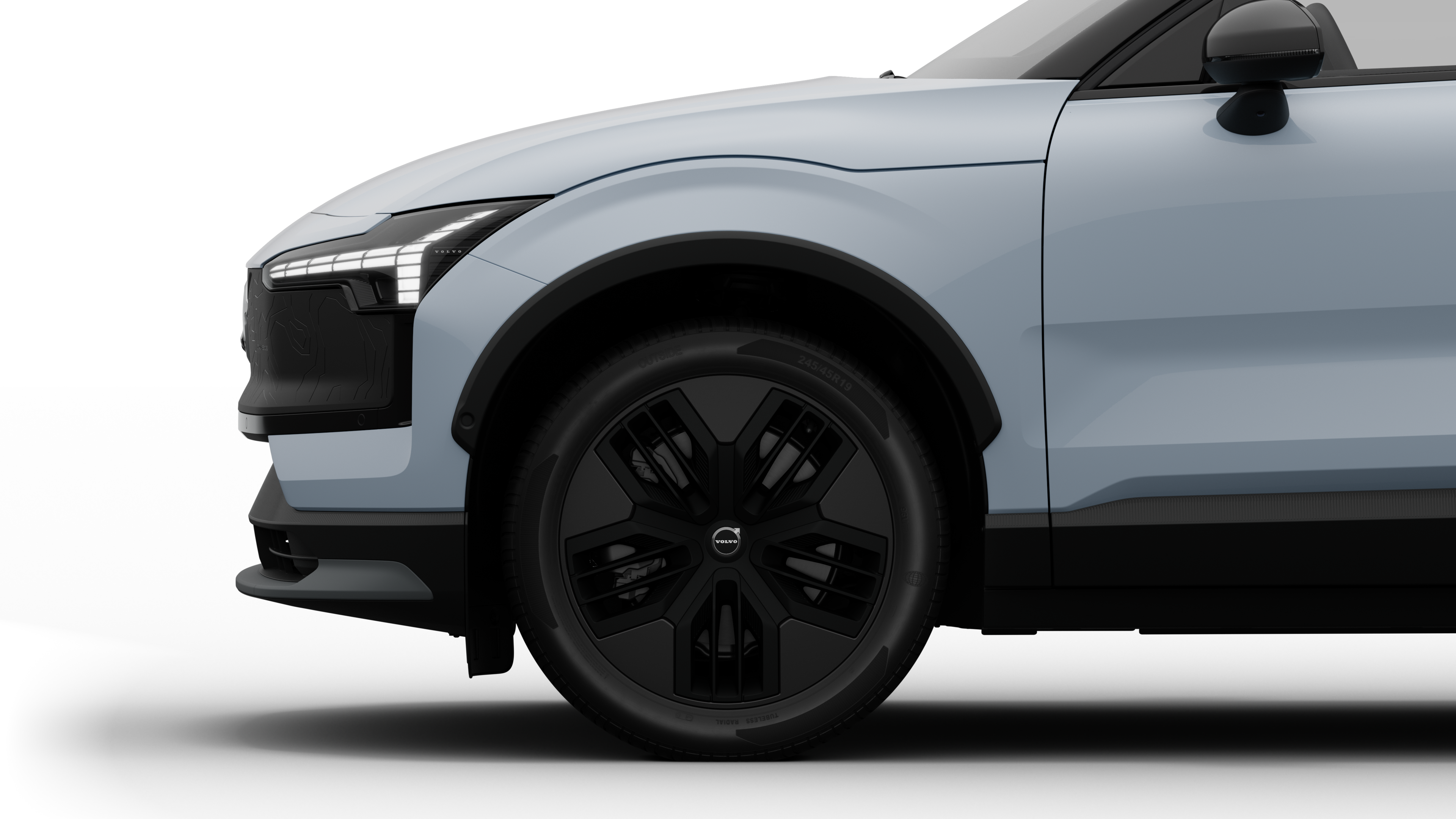沃尔沃汽车外部侧视图聚焦于前轮和挡泥板，背景为朴素的工作室背景。