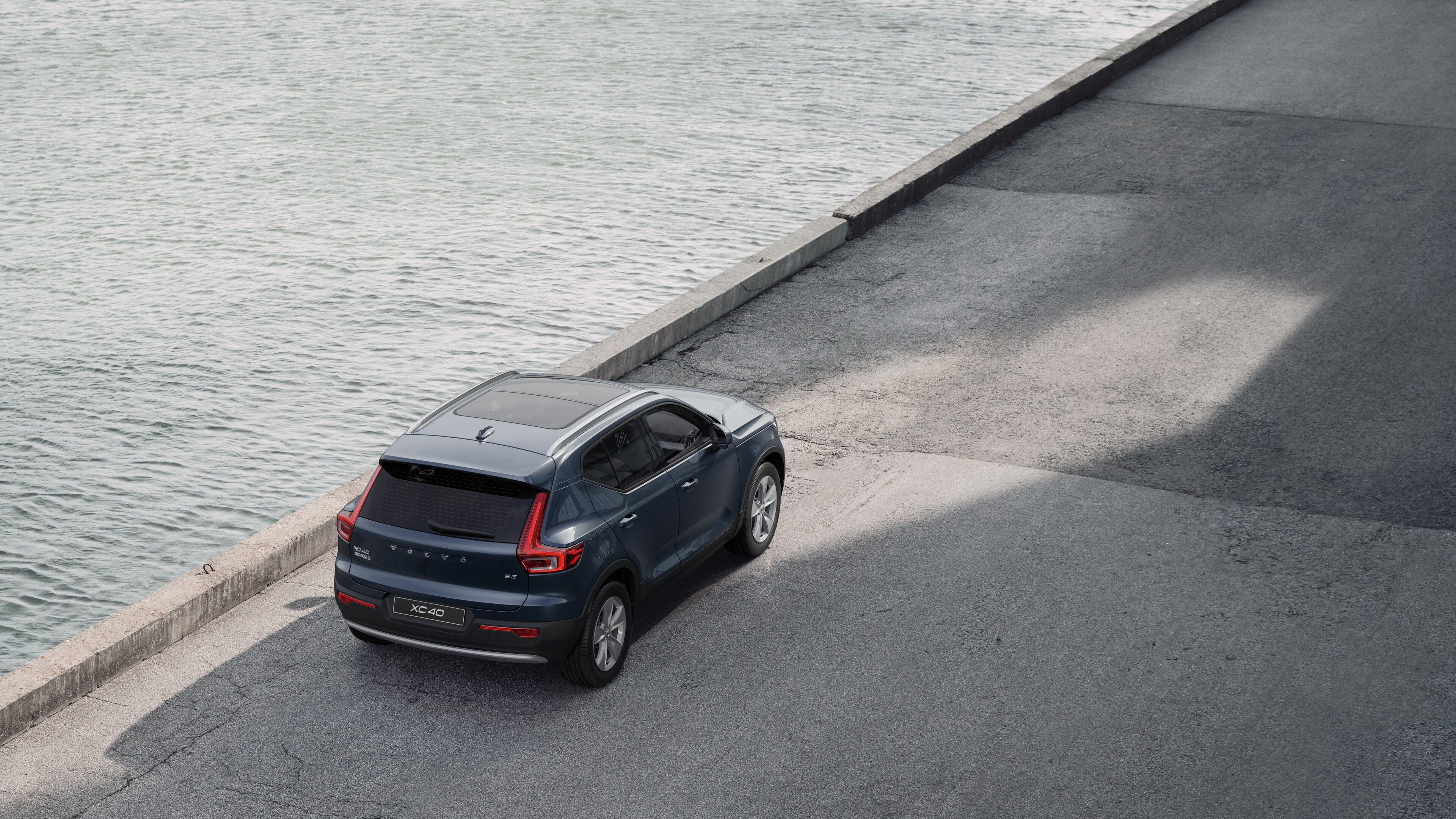 沃尔沃汽车后视图停在安静的水边街道上，以铺好的走道和水为背景。