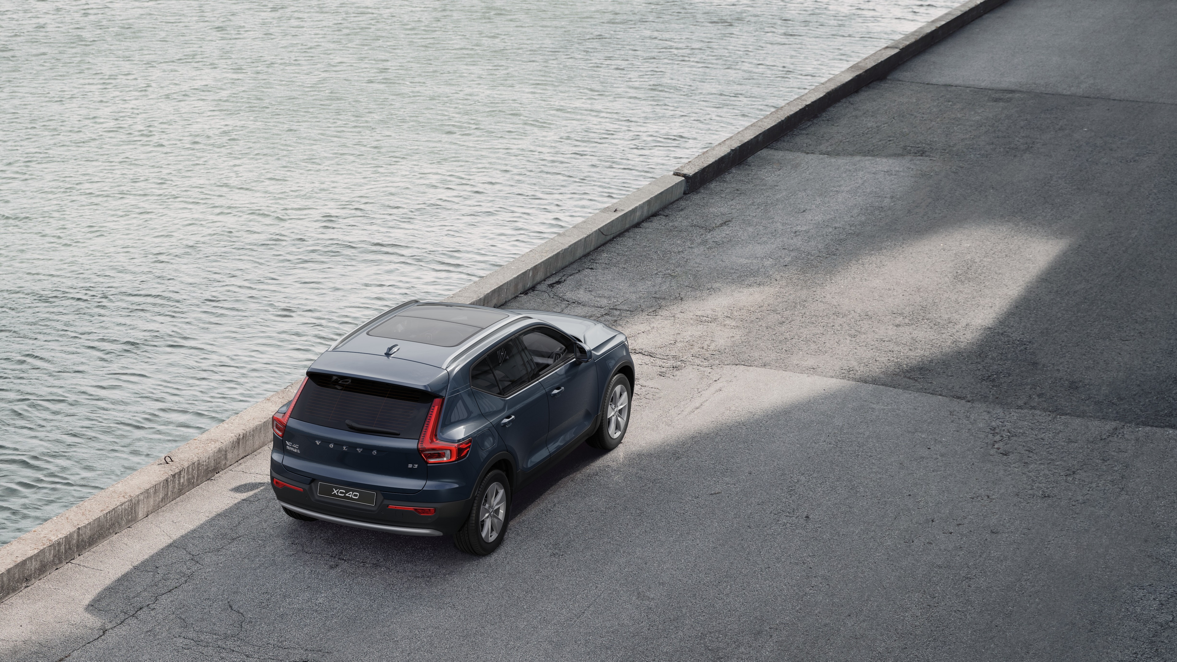 沃尔沃汽车后视图停在安静的水边街道上，以铺好的走道和水为背景。