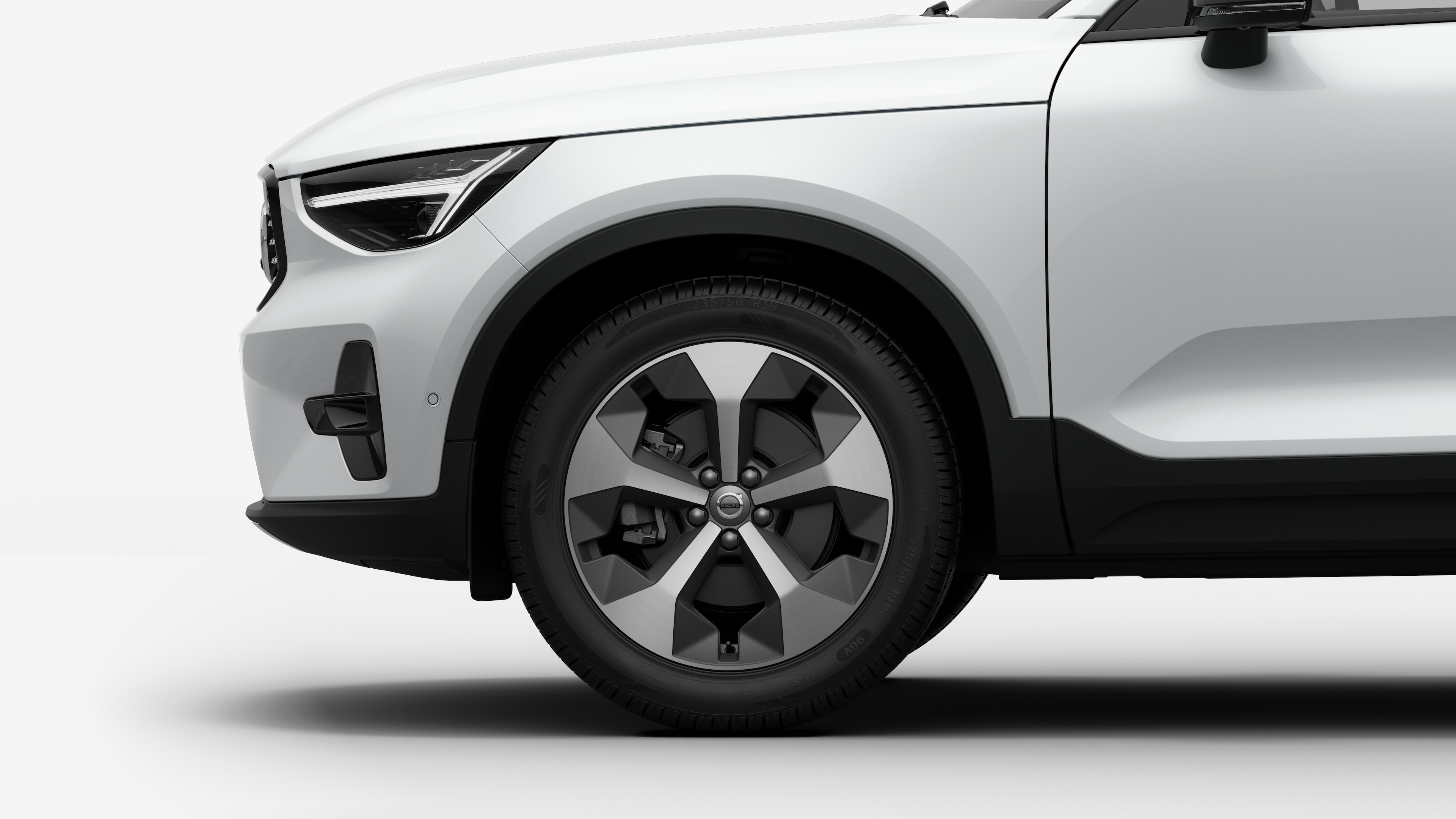 沃尔沃汽车外部侧视图聚焦于前轮和挡泥板，背景为朴素的工作室背景。