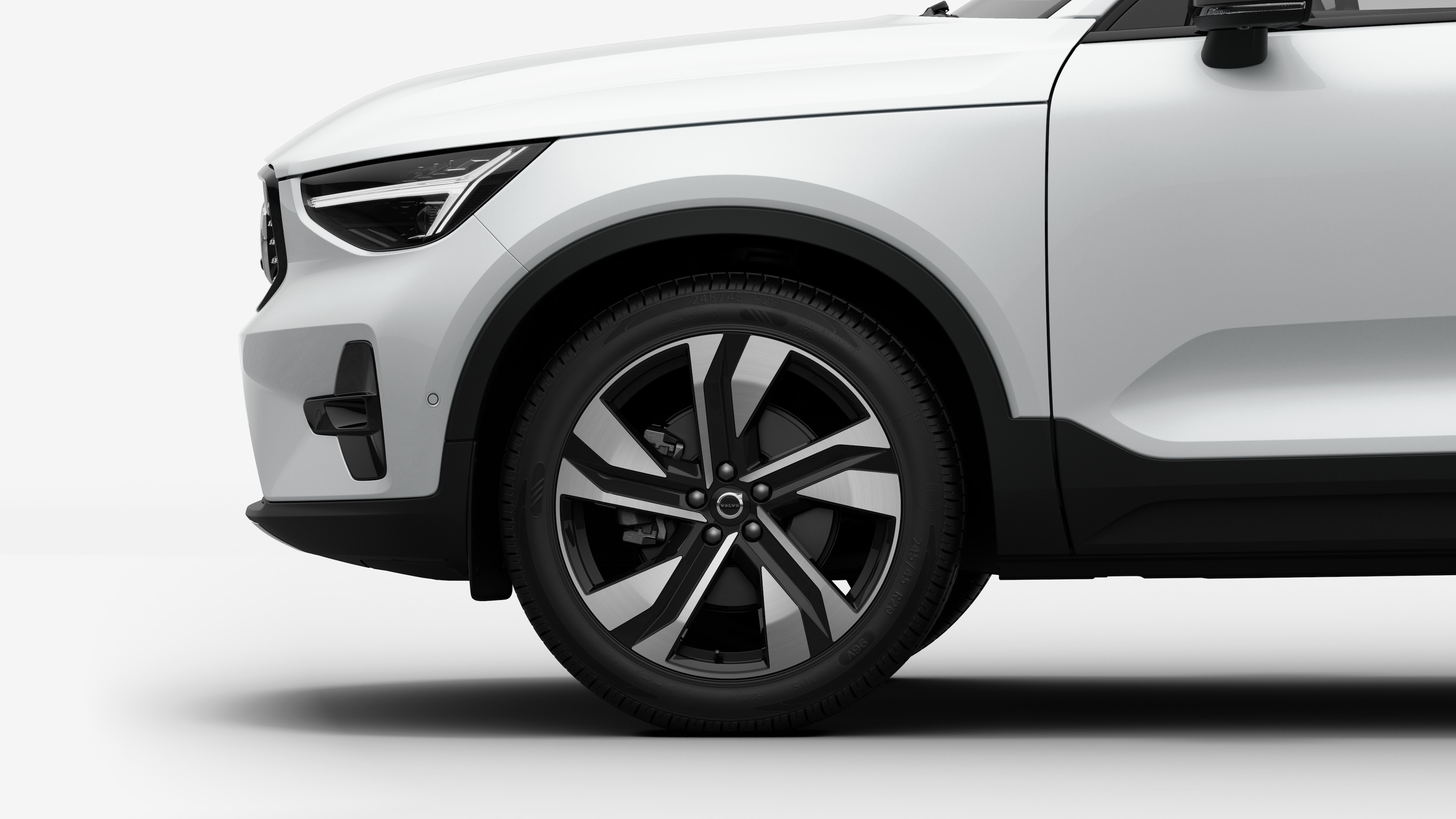 沃尔沃汽车外部侧视图聚焦于前轮和挡泥板，背景为朴素的工作室背景。