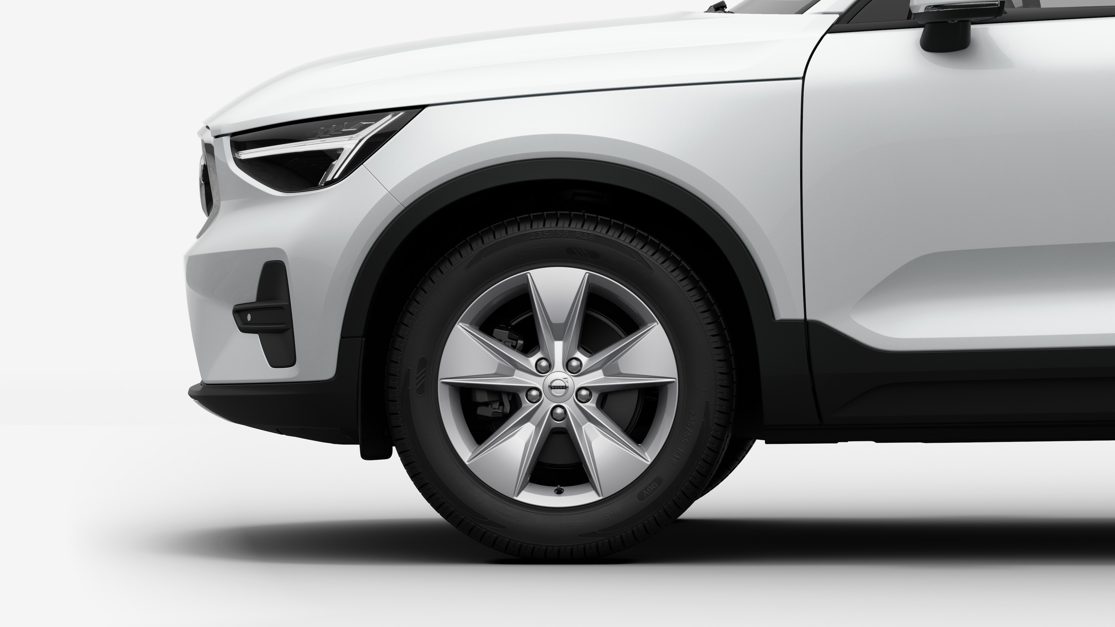 沃尔沃汽车外部侧视图聚焦于前轮和挡泥板，背景为朴素的工作室背景。