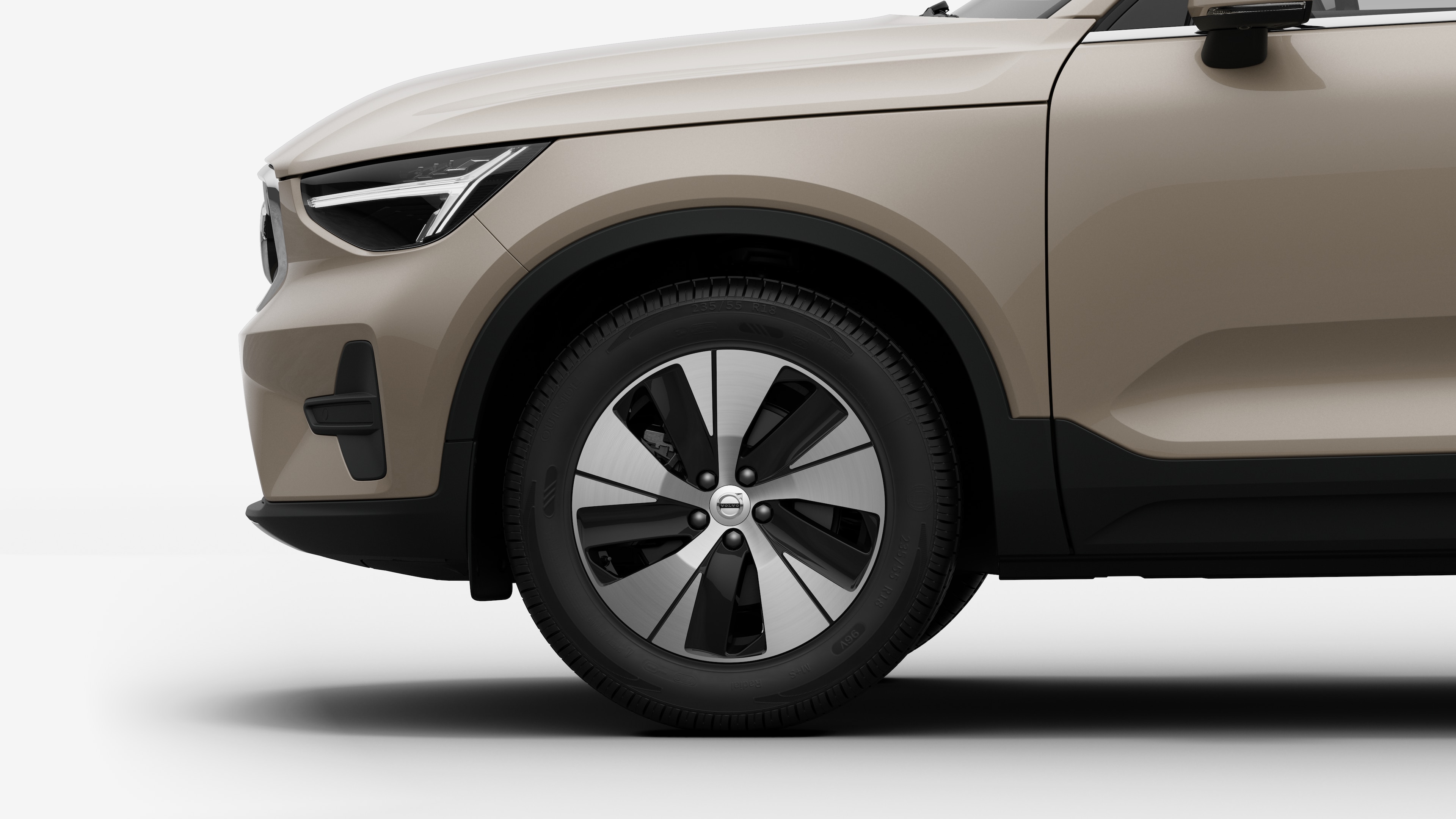 沃尔沃汽车外部侧视图聚焦于前轮和挡泥板，背景为朴素的工作室背景。