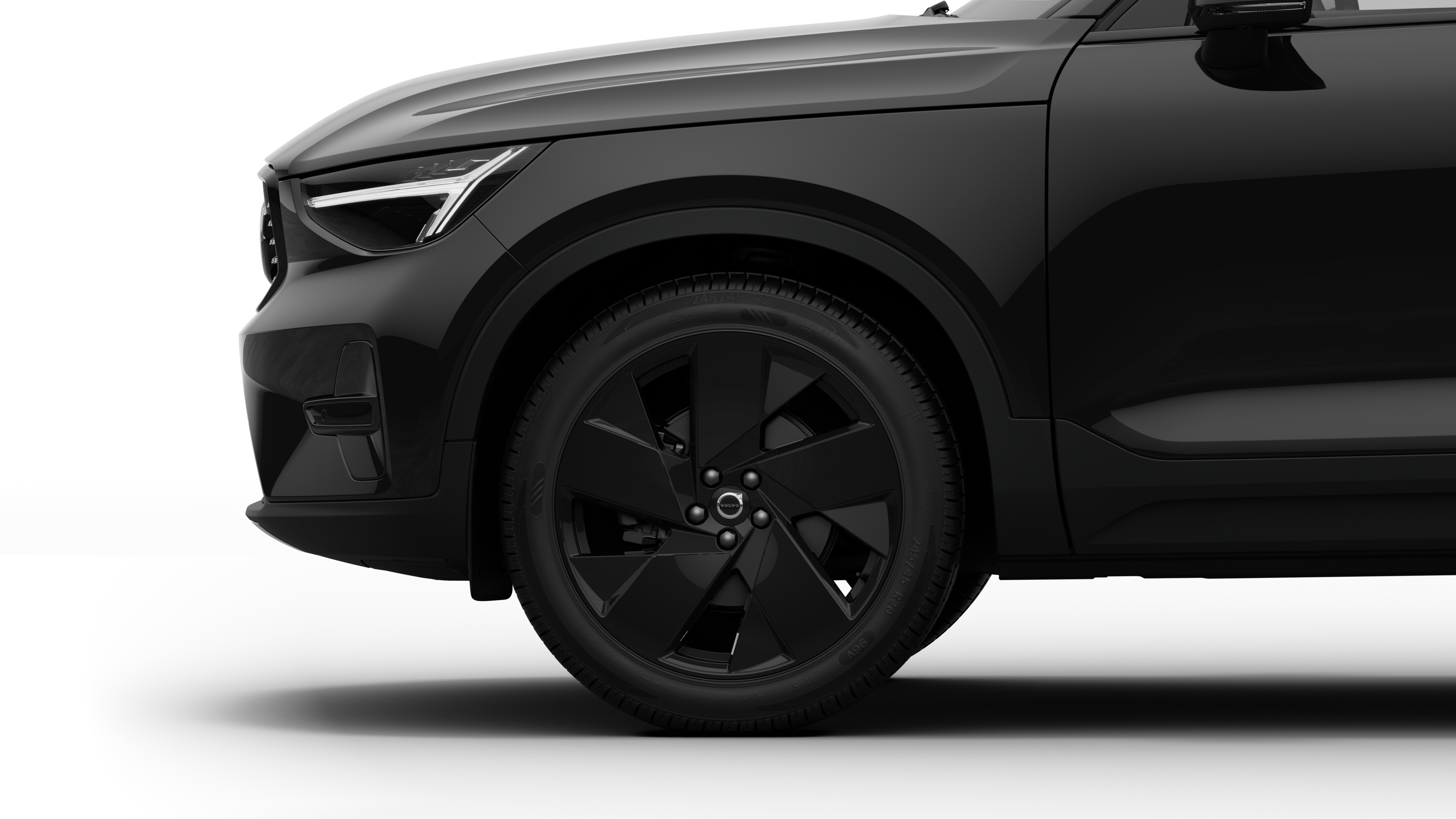 沃尔沃汽车外部侧视图聚焦于前轮和挡泥板，背景为朴素的工作室背景。