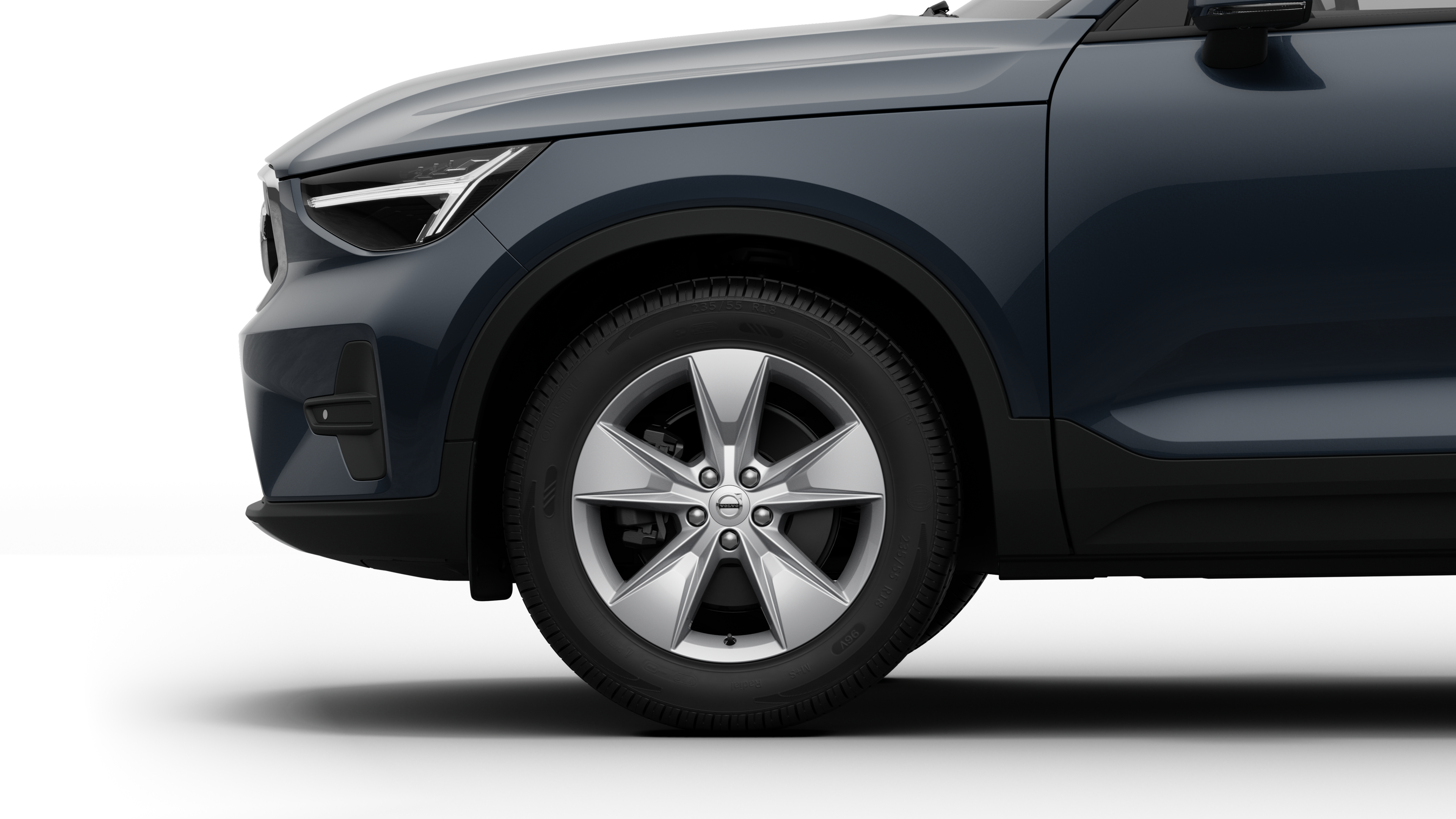 沃尔沃汽车外部侧视图聚焦于前轮和挡泥板，背景为朴素的工作室背景。