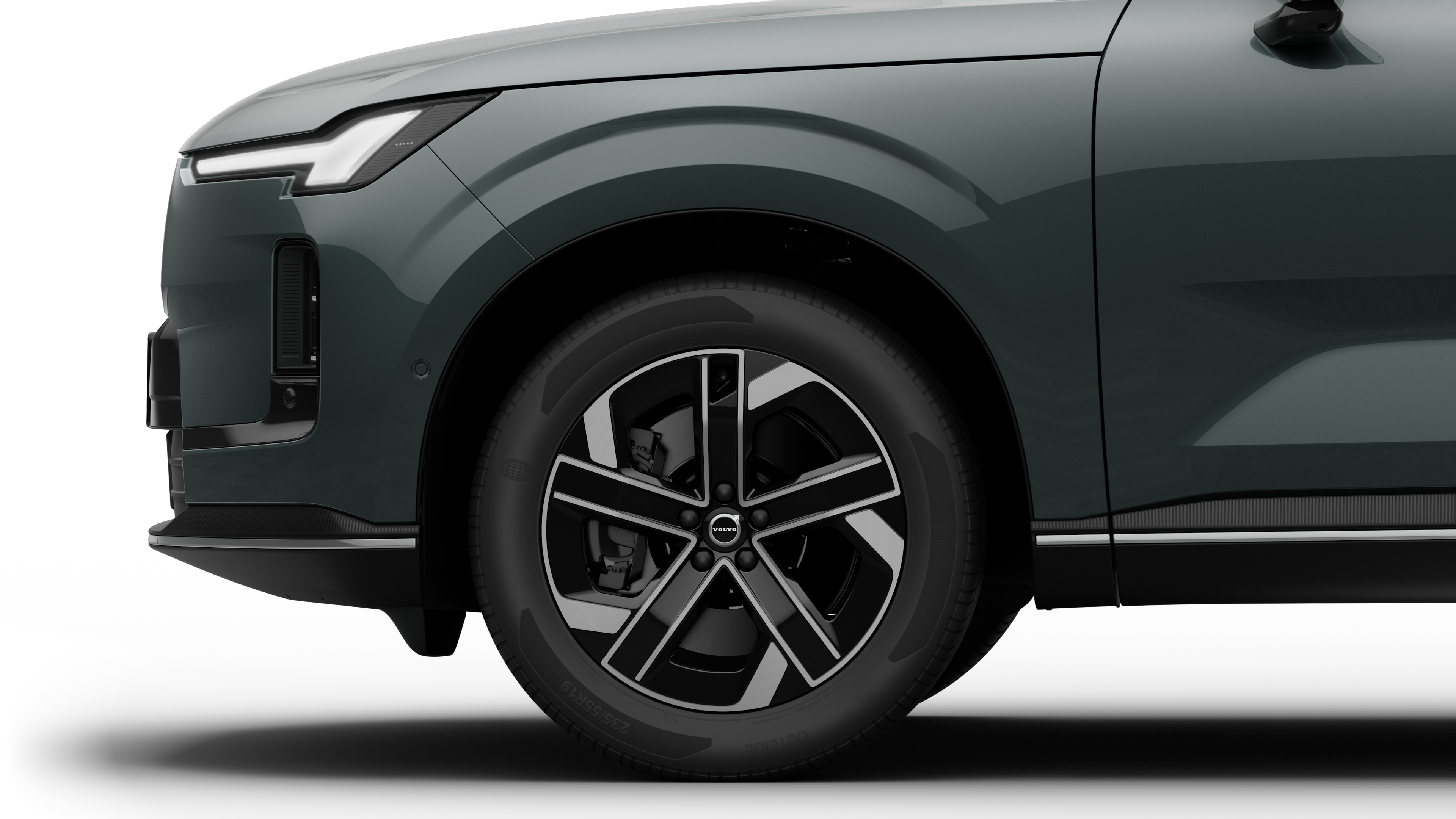 沃尔沃汽车外部侧视图聚焦于前轮和挡泥板，背景为朴素的工作室背景。